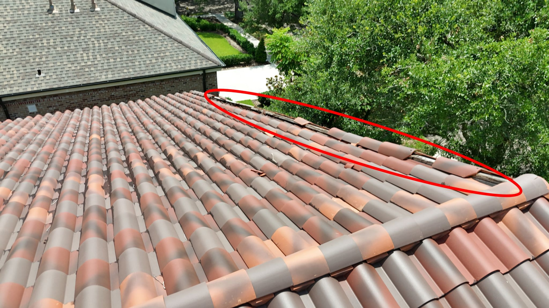 Drone inspection markup circling missing terra cotta tiles and exposed decking along a hip run in Metairie Louisiana