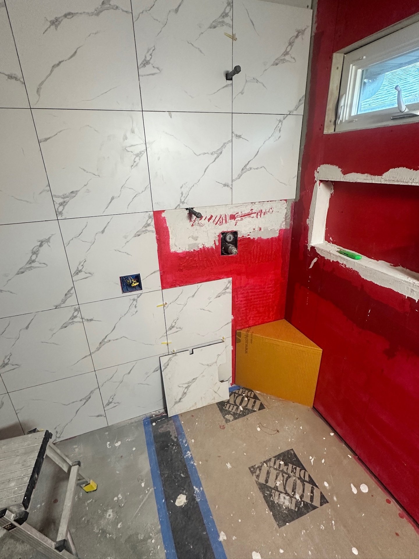 Tile wrapping around Schluter shower bench with valve and niche openings still exposed in Metairie master bath