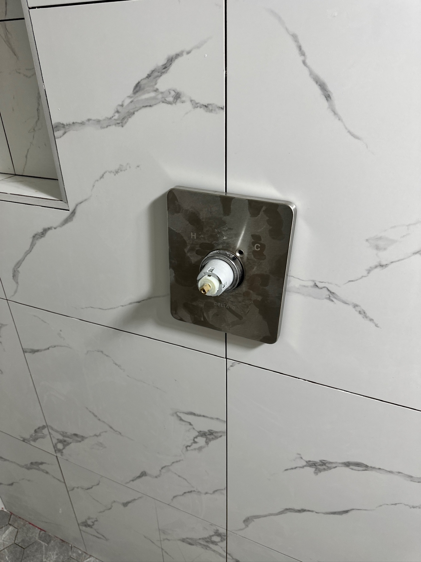 Close-up of Delta brushed nickel square shower valve trim on marble-look porcelain in Metairie master bath
