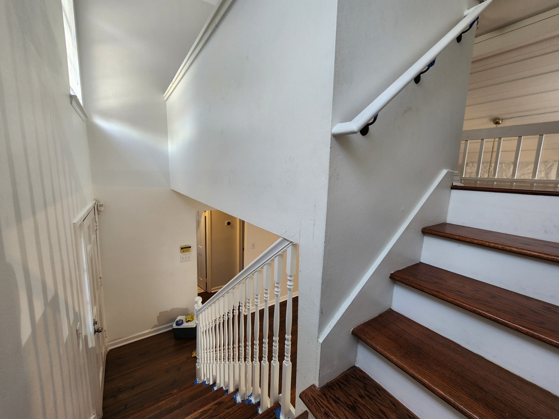 Finished upper stair flight with wall-mounted ADA style continuous handrail on black brackets alongside refinished oak treads in a Kenner LA home