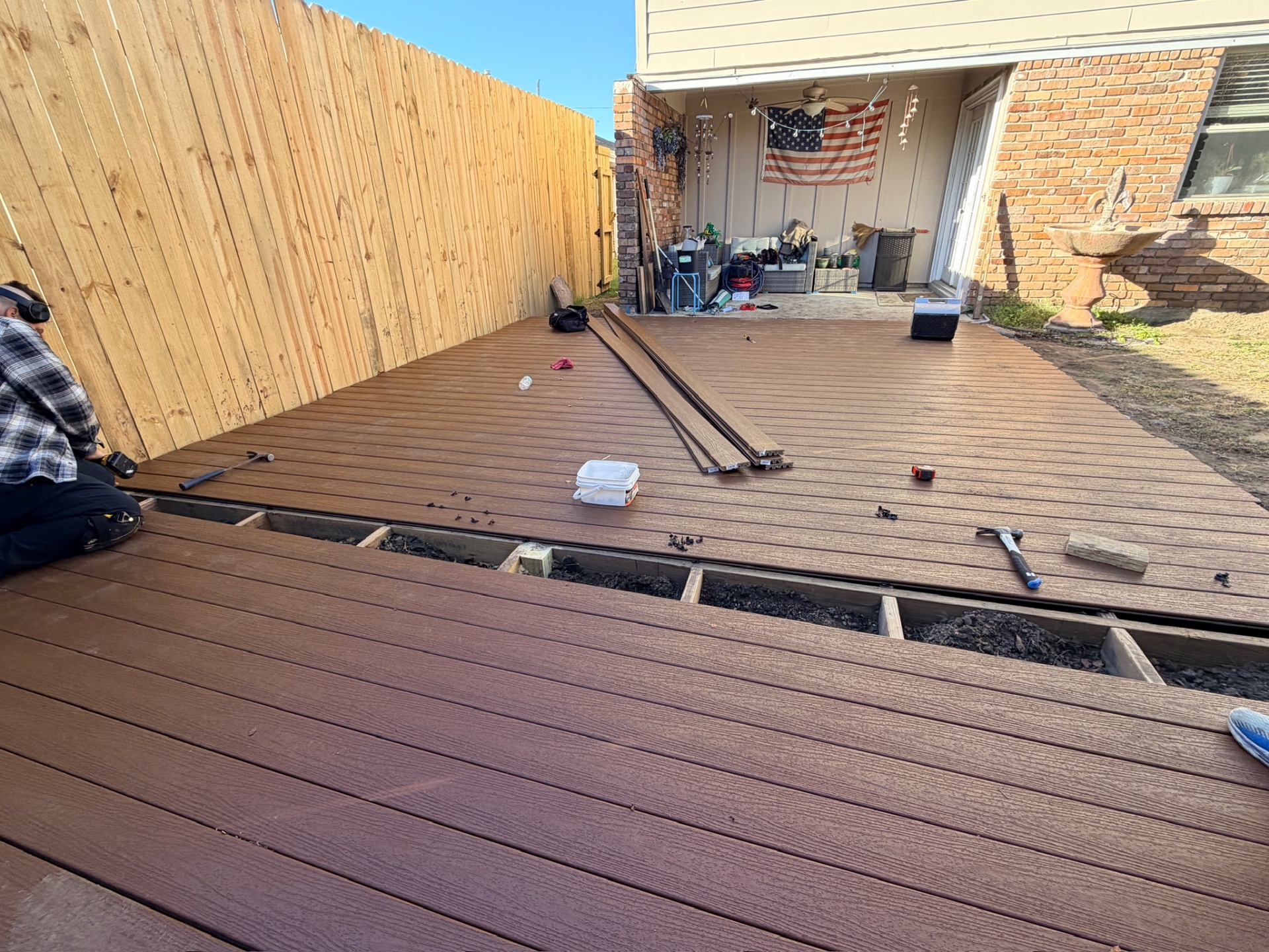 Composite deck planks going in against new picket fence in Metairie Louisiana backyard