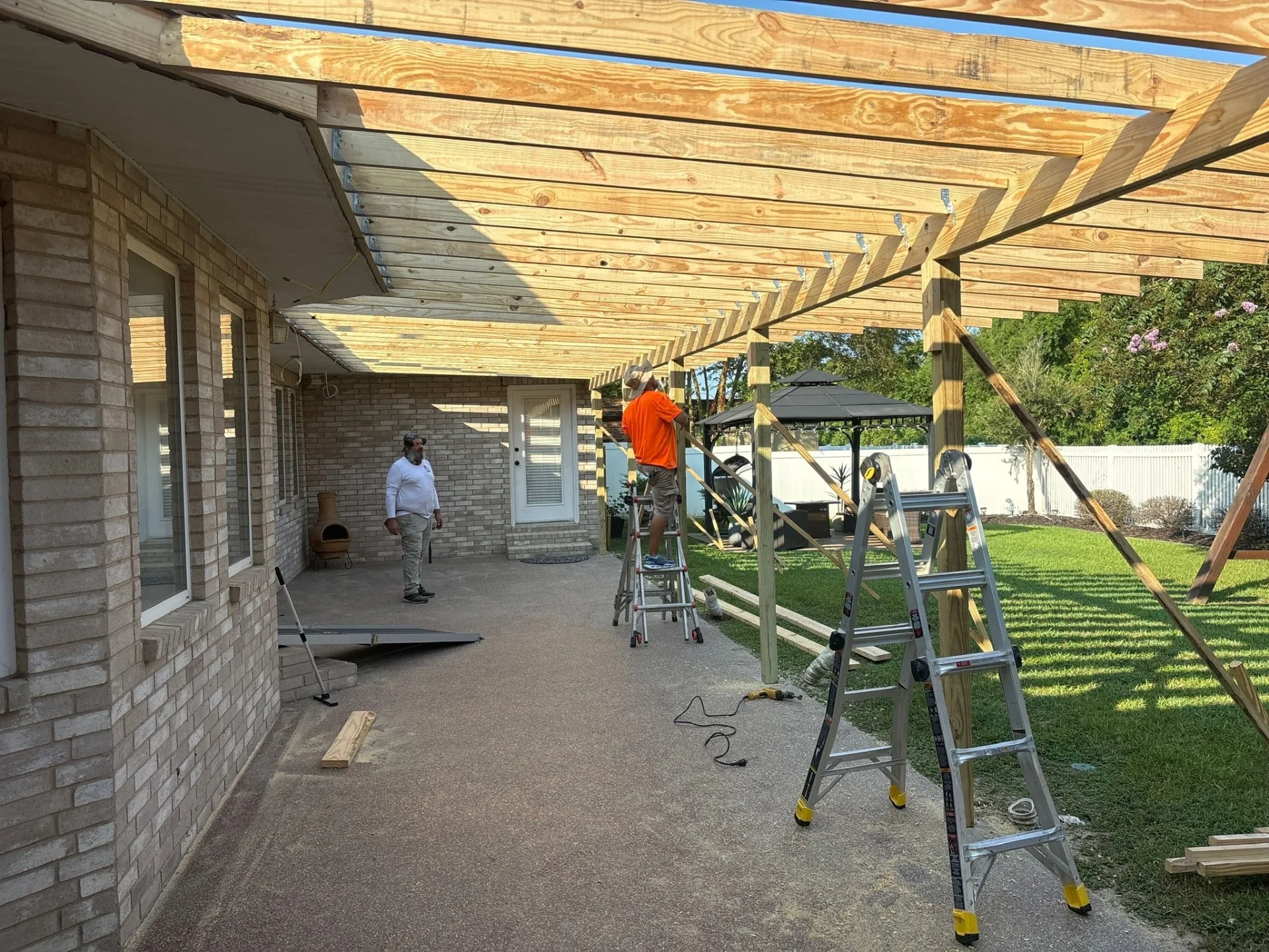 New pressure-treated rafters and roof decking installed overhead during complete covered patio replacement at Destrehan Louisiana home by Cajun Home Services