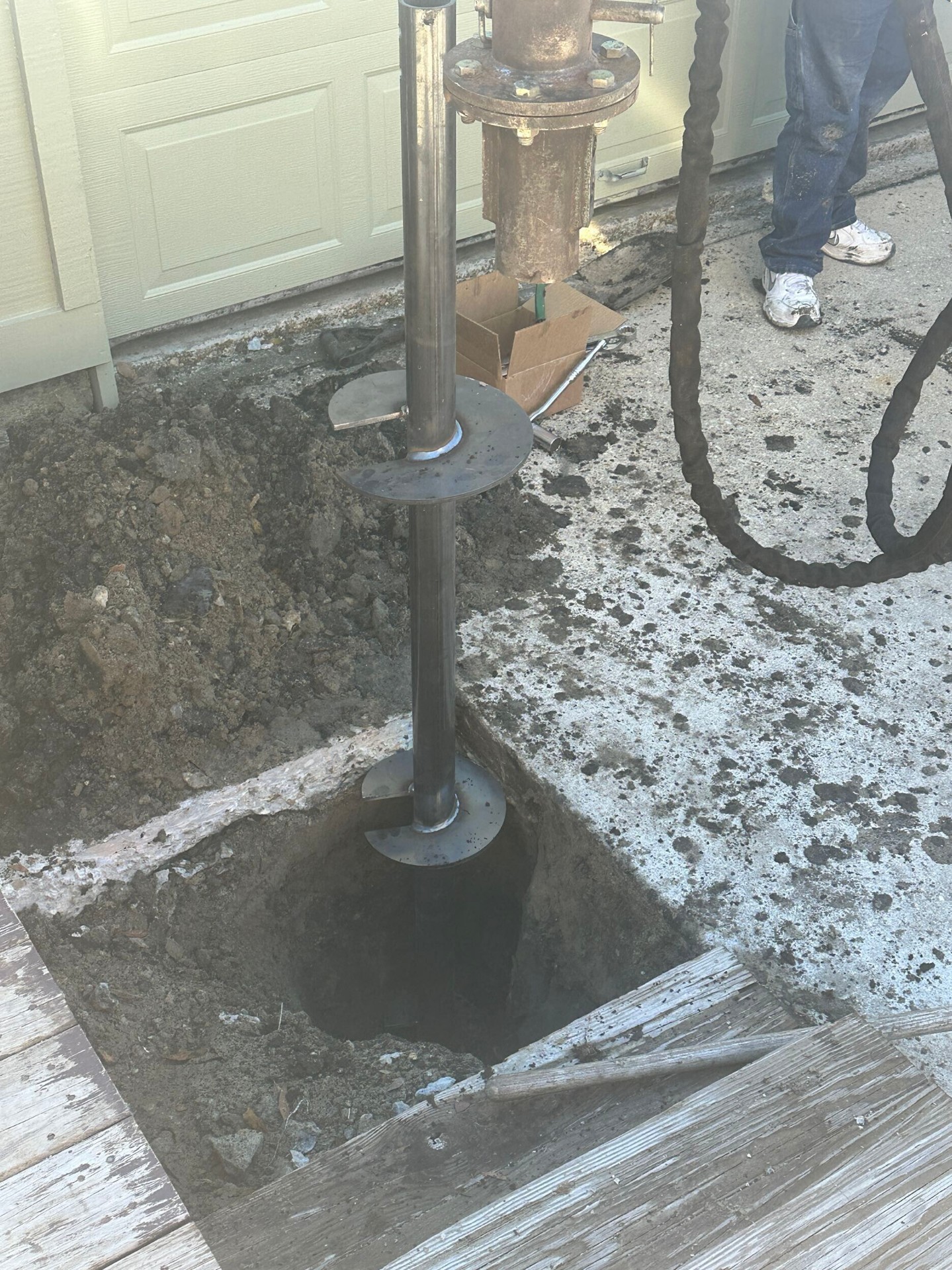 Helical pier being driven at Blanke Street Metairie home for foundation reinforcement under second-story addition by Cajun Home Services