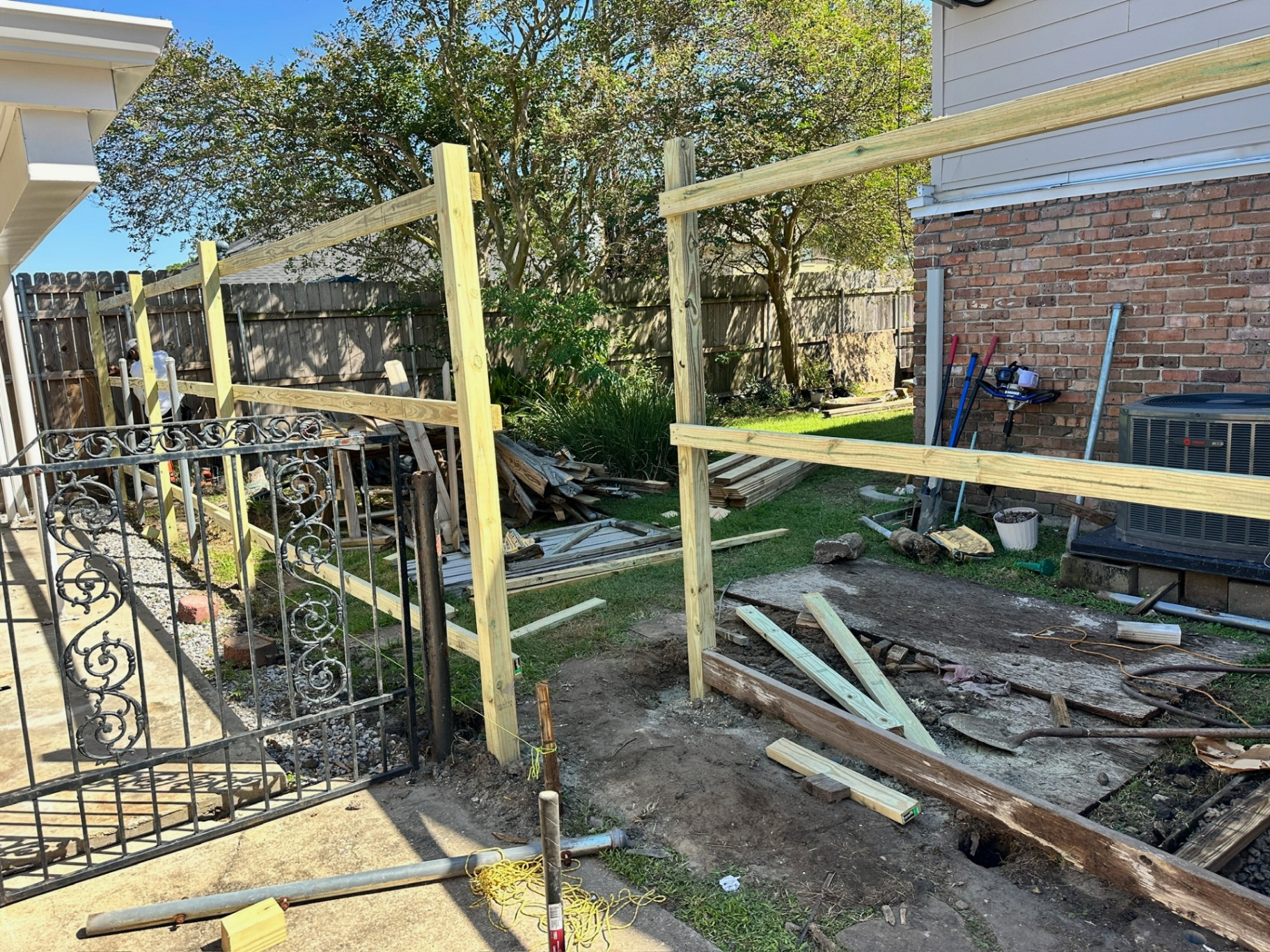 Treated 4x4 posts and 2x4 top and bottom rails installed at the front driveway gate area of the Metairie home before pickets go on
