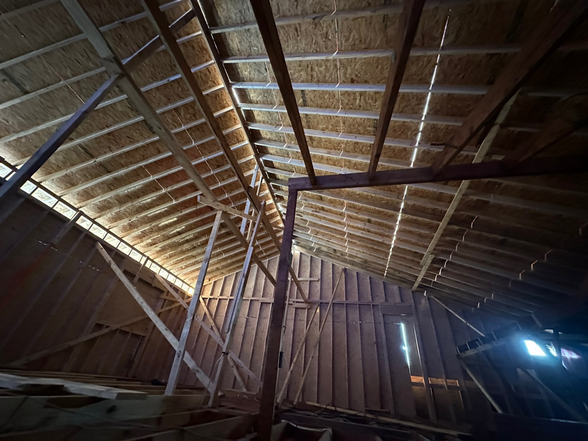 Overhead interior view of new roof rafters with OSB decking partially installed on Metairie second-floor addition