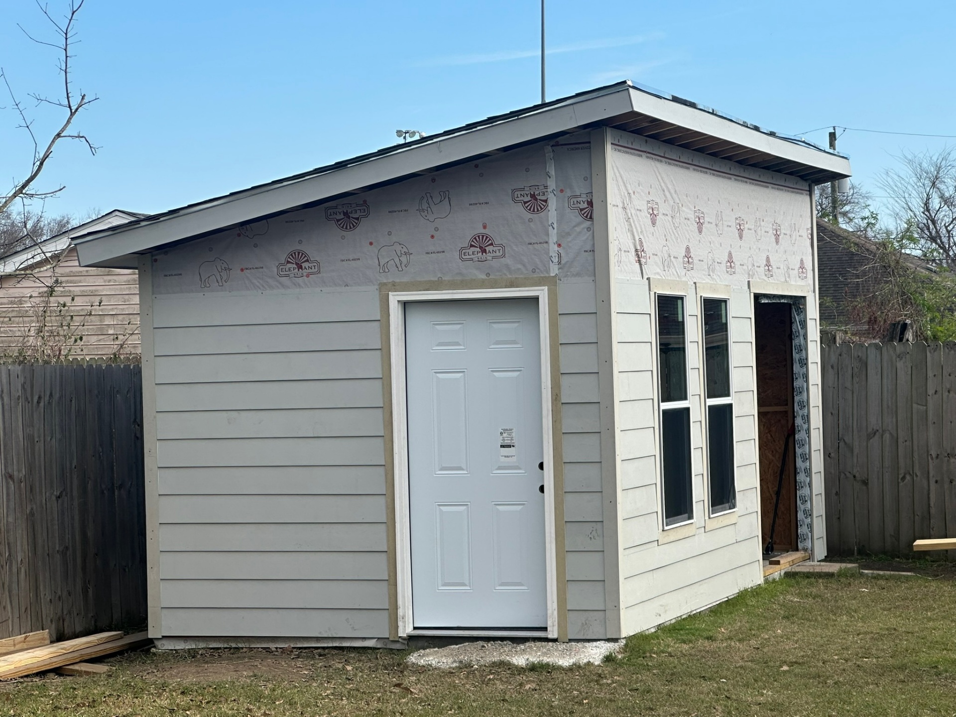 Metairie shed front elevation with primed Hardie siding installed on lower half and exposed Elephant Skin housewrap above before paint