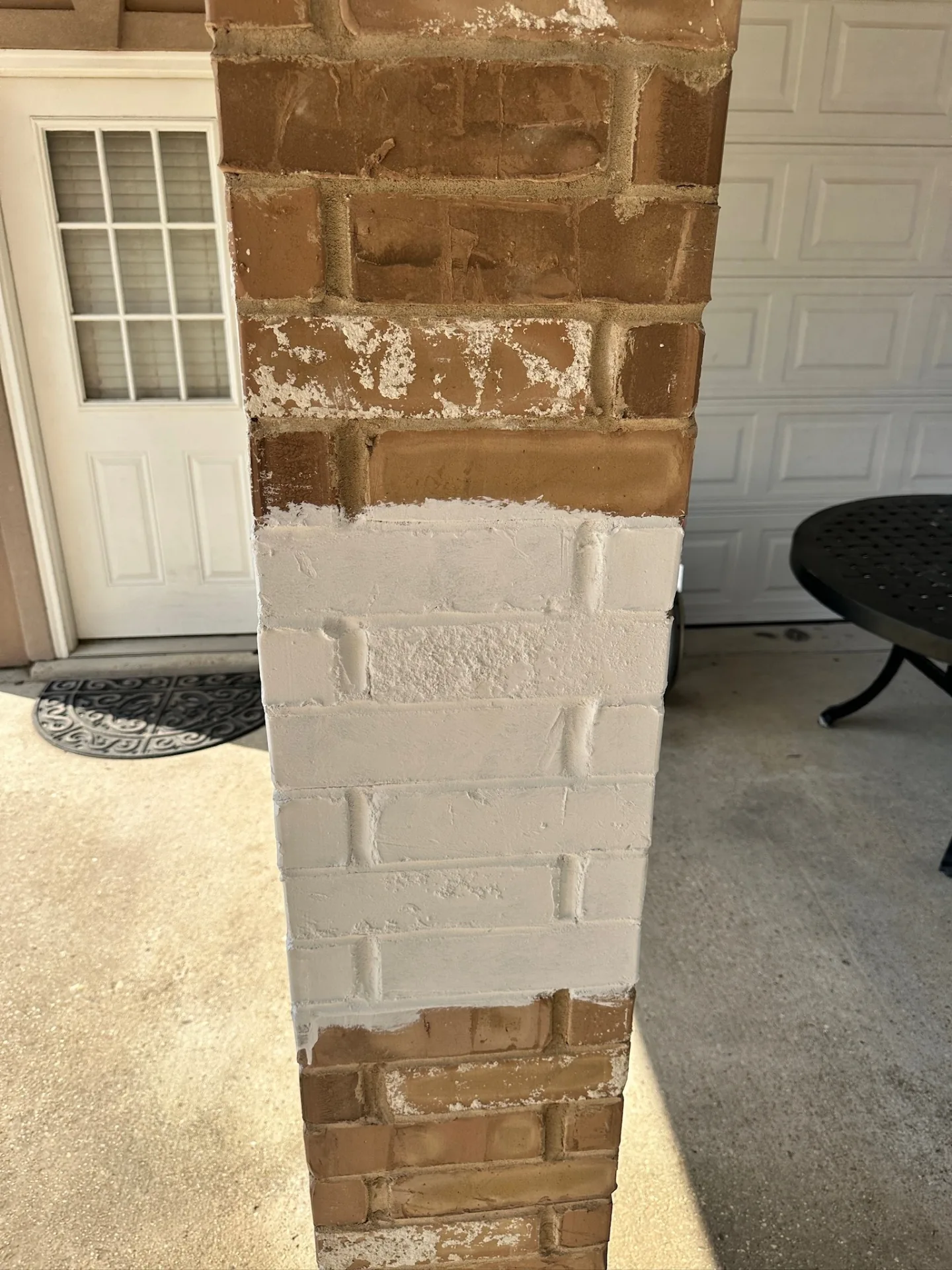 Close-up detail of limewash finish being applied to new brick-wrapped patio post at Destrehan Louisiana home by Cajun Home Services