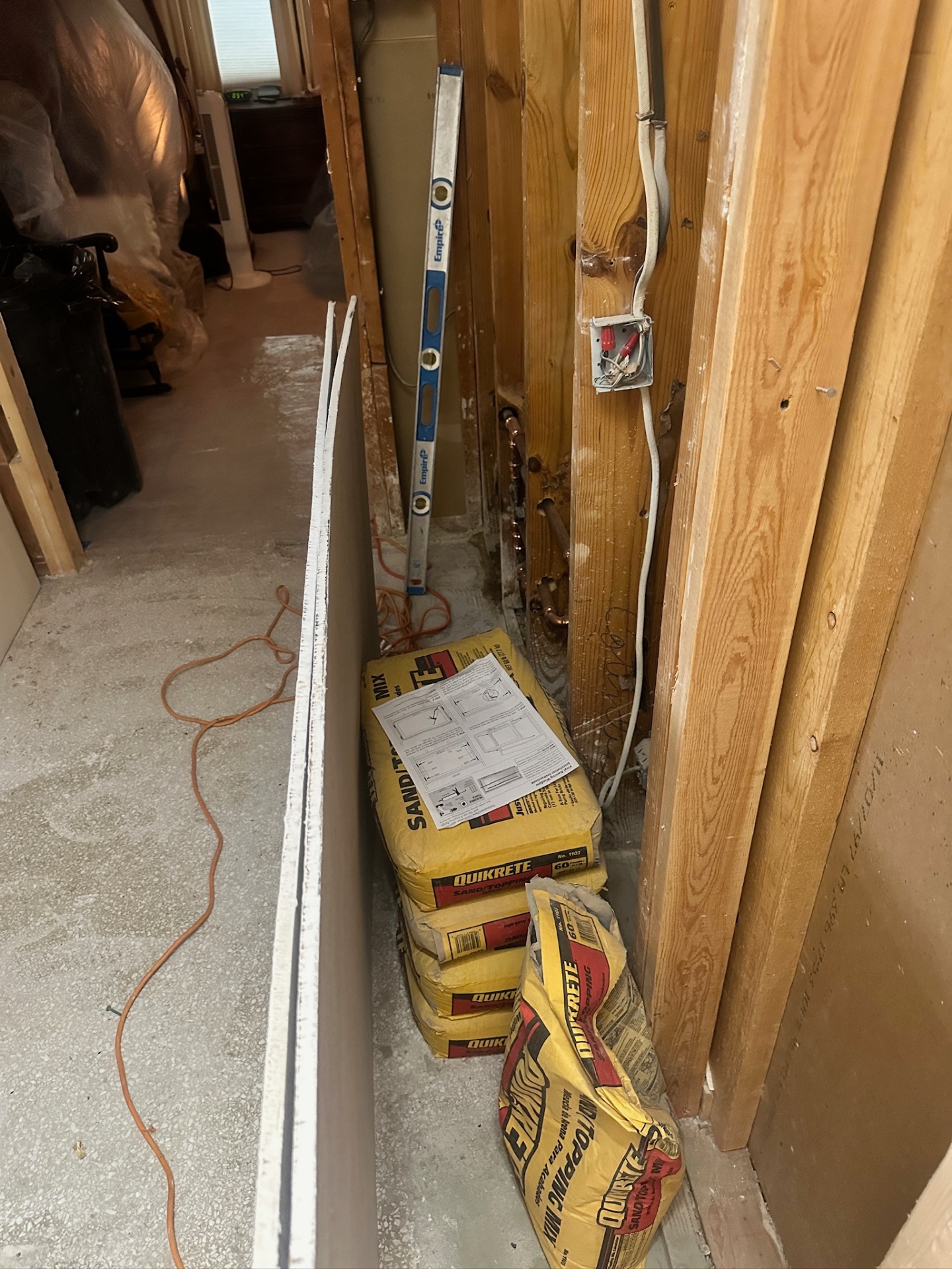 Quikrete sand-topping mix staged in the framed master bath hallway during Metairie remodel