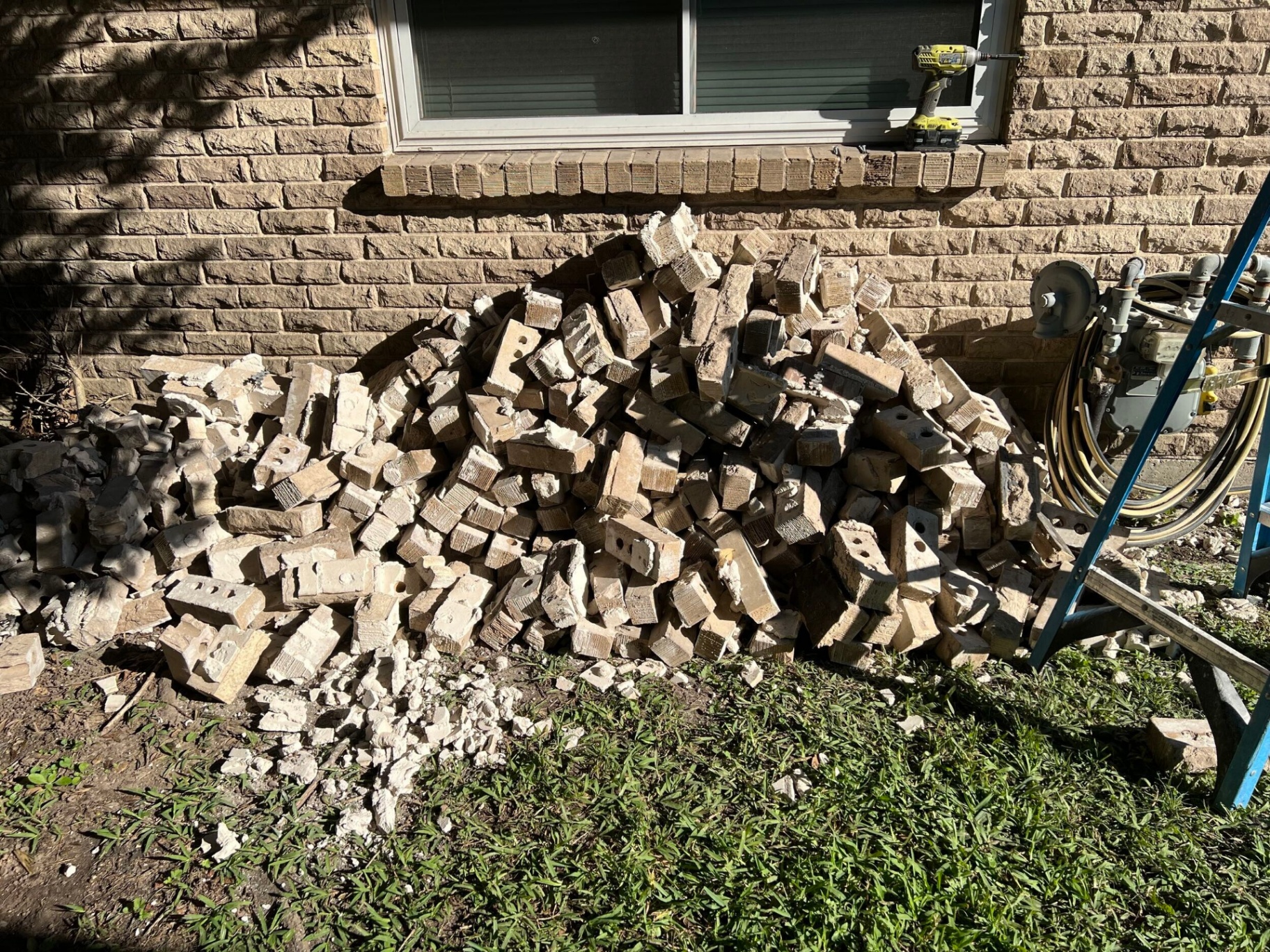 Pile of salvaged and broken brick from the damaged Gretna exterior wall staged for disposal and color-match sourcing