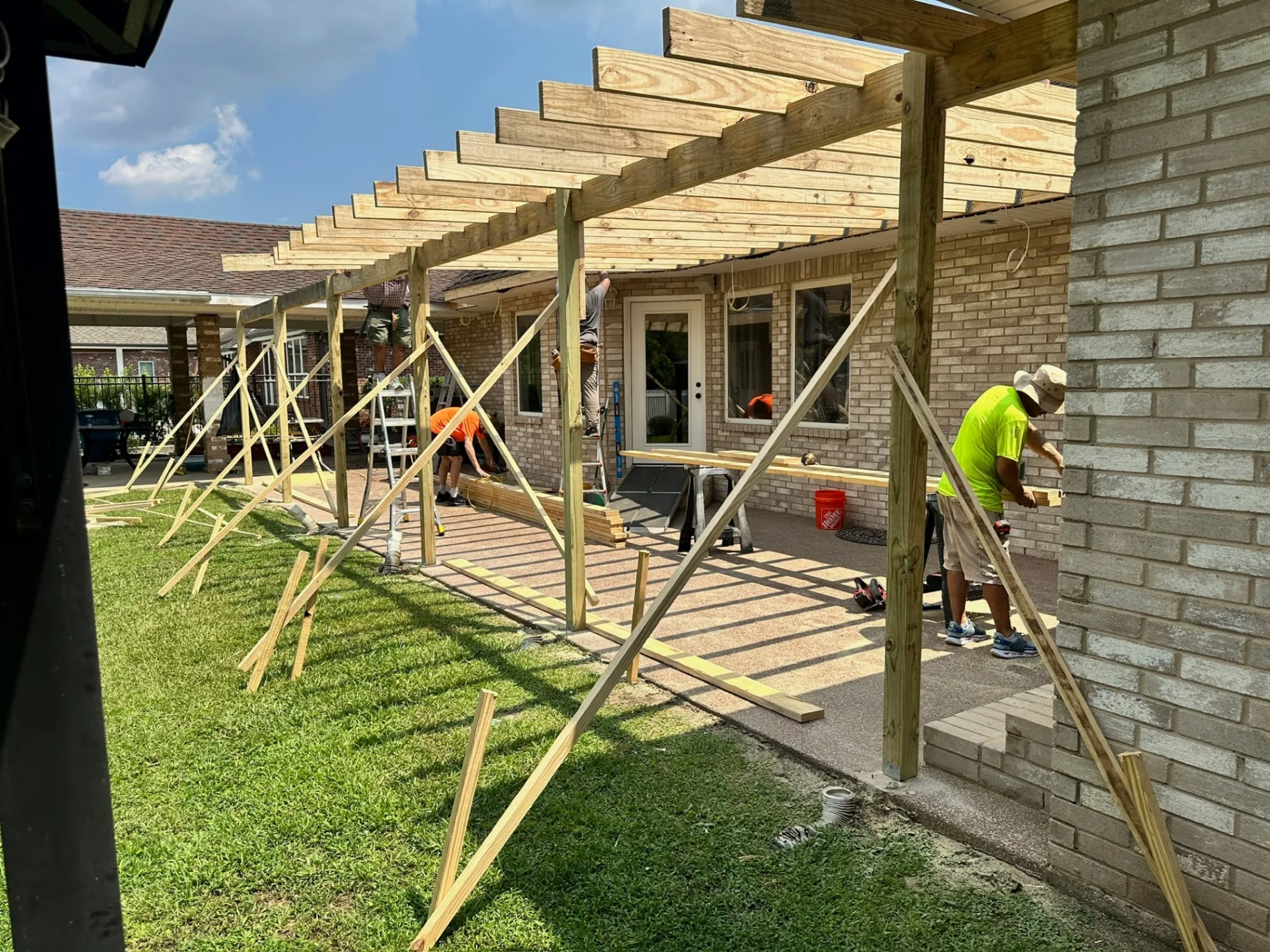 Cajun Home Services crew setting pressure-treated rafters and bracing on new covered patio framing at Destrehan Louisiana home