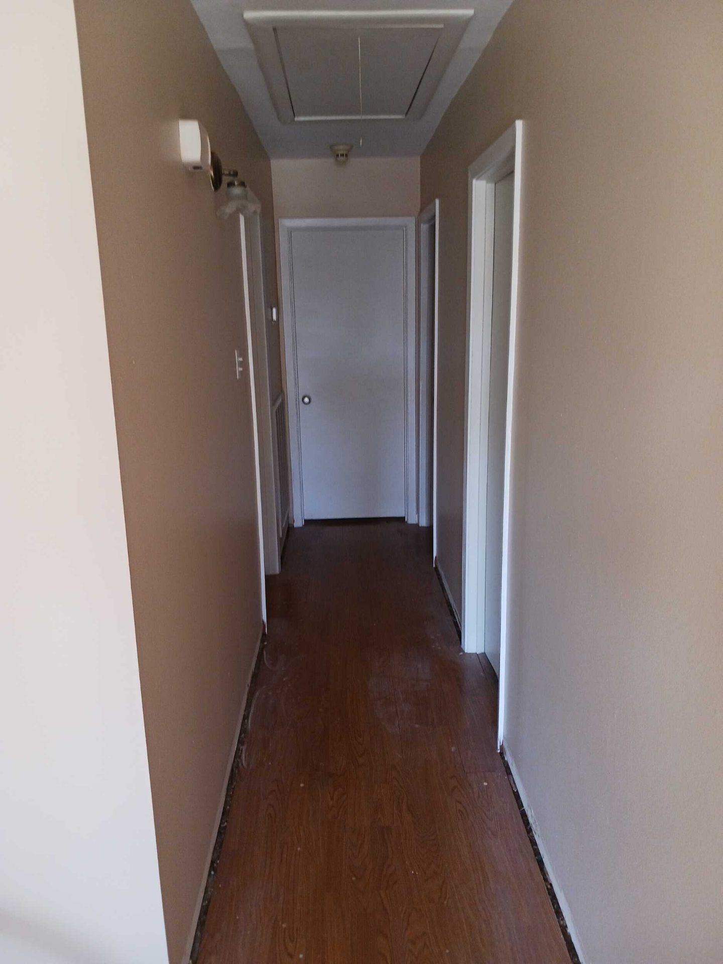 Finished hallway in the Gretna home after insurance repair with freshly repainted walls, doors, and trim in warm neutral tones