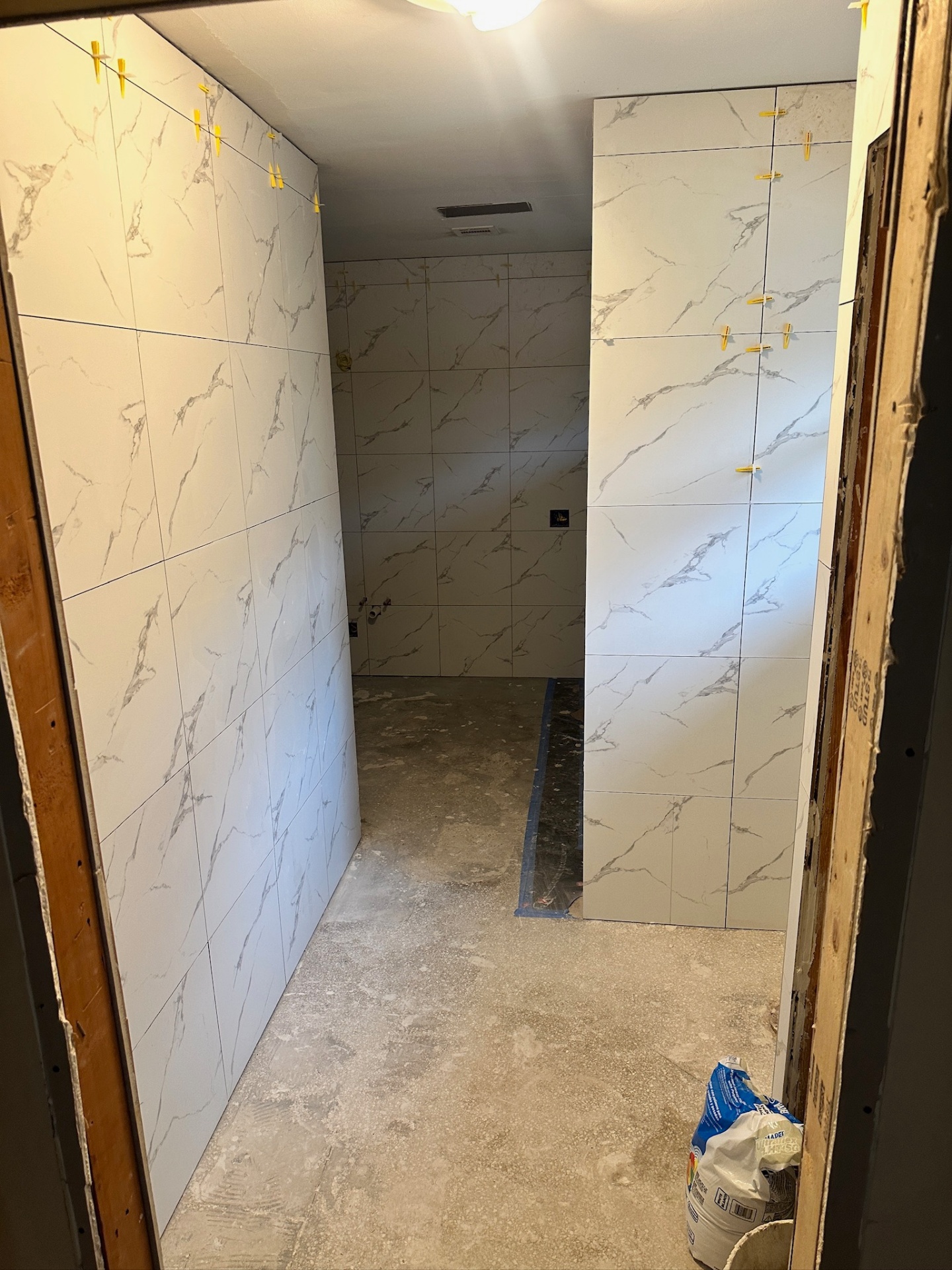 Marble-look large-format porcelain tile going up in walk-in shower with leveling clips in Metairie master bath