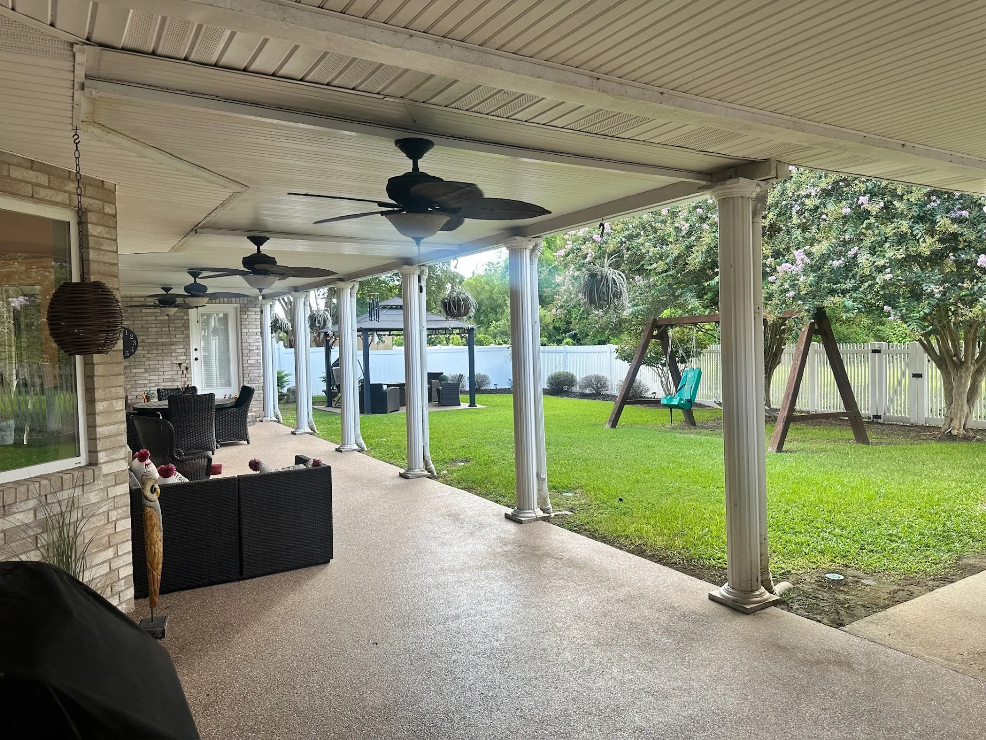 Before — existing covered patio with aged aluminum pan ceiling and white fluted columns on Destrehan Louisiana home before complete replacement by Cajun Home Services