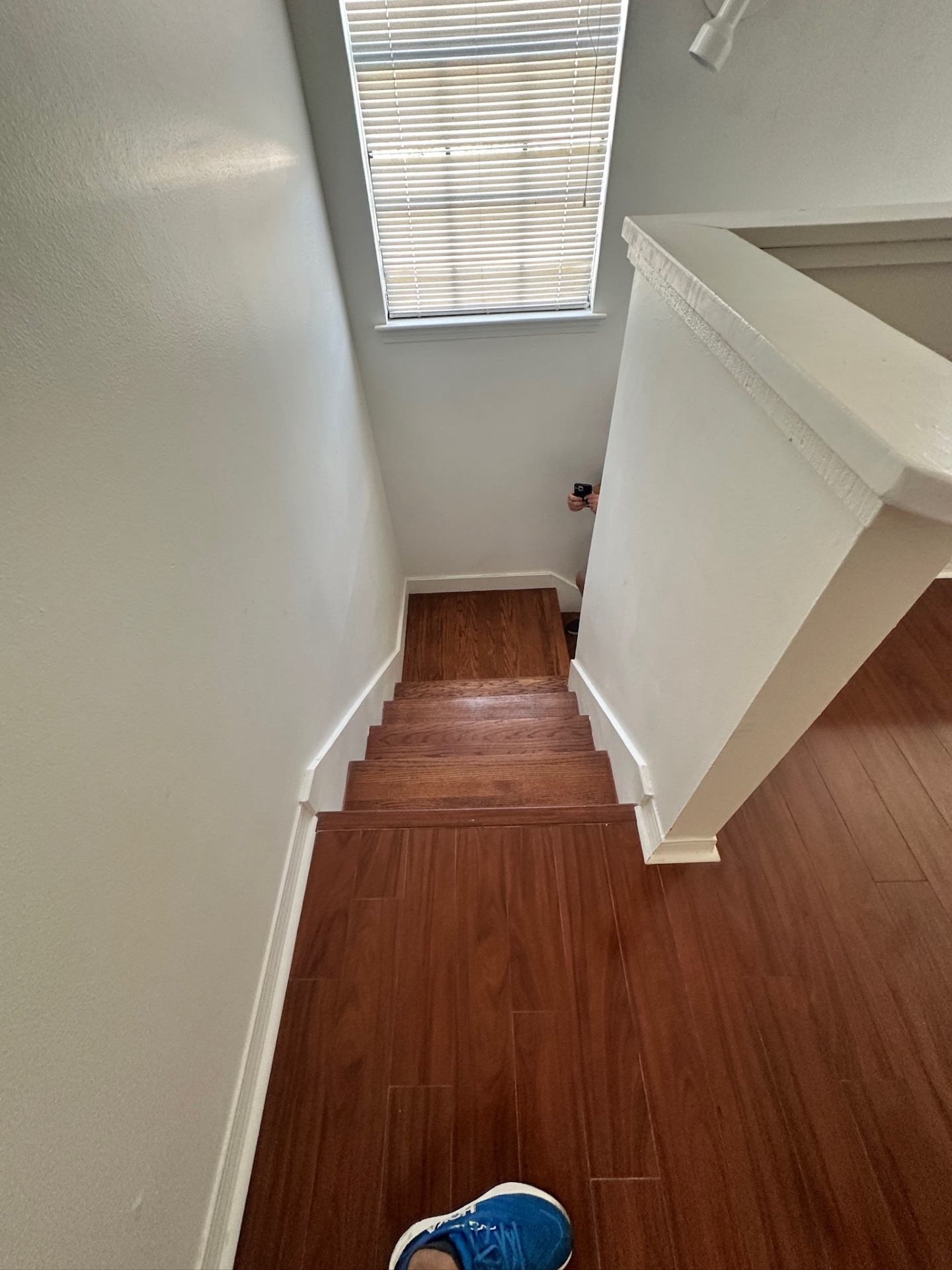 Finished view from the top landing looking down the newly built stair rail with white balusters and refinished oak treads in Kenner LA