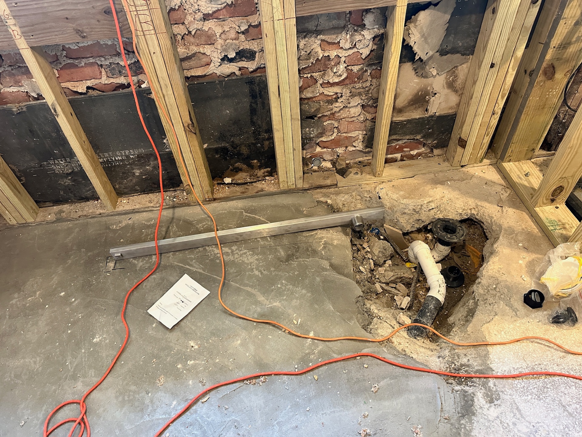 Close view of core-drilled slab exposing old cast iron drain and PVC transition in Metairie master bath