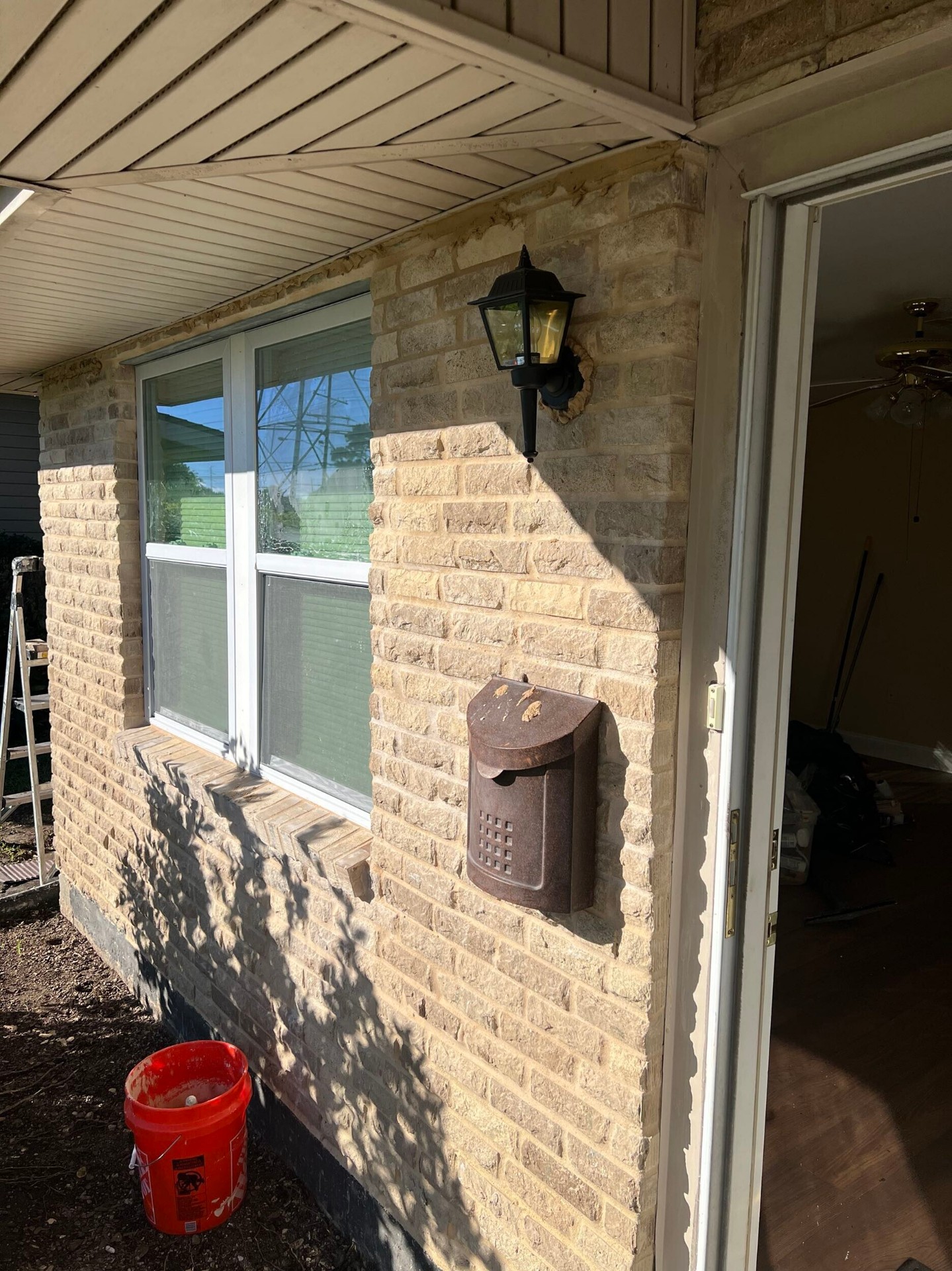 Wide exterior finish view of the rebuilt Gretna front elevation with new brick veneer, lantern light, mailbox, and windows fully restored after the truck impact