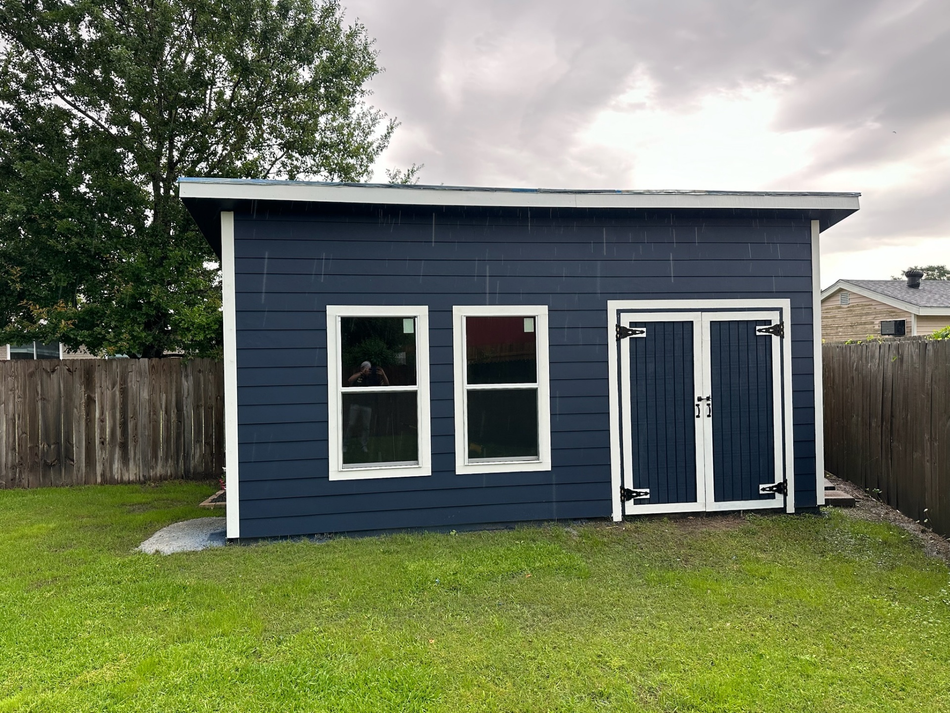 Wide view of finished custom shed in rain Metairie Louisiana backyard