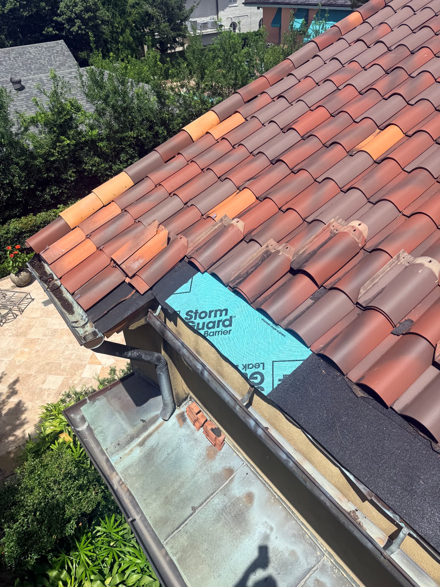 Replacement terra cotta tiles staged over new underlayment at the eave of a Metairie Louisiana tile roof