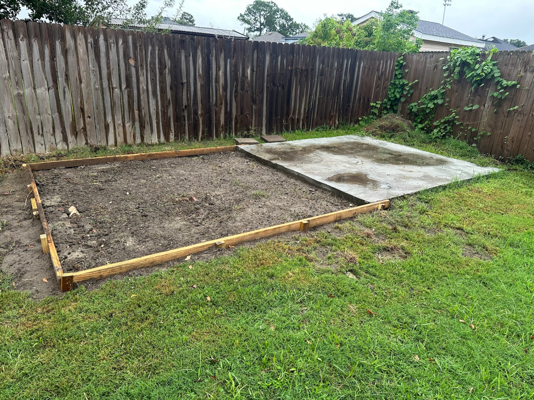 Site prep with pressure-treated form boards set next to existing concrete slab for new Metairie backyard shed