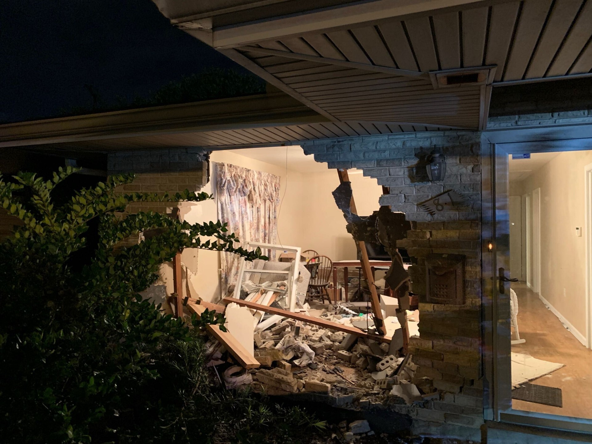 Exterior night view of pickup truck through the brick veneer wall of a Gretna Louisiana home with debris in the flower bed