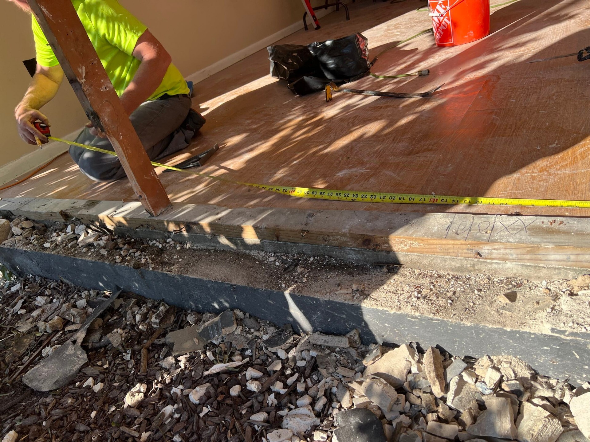 Crew measuring the damaged slab edge and sill plate on a Gretna insurance repair project before re-framing