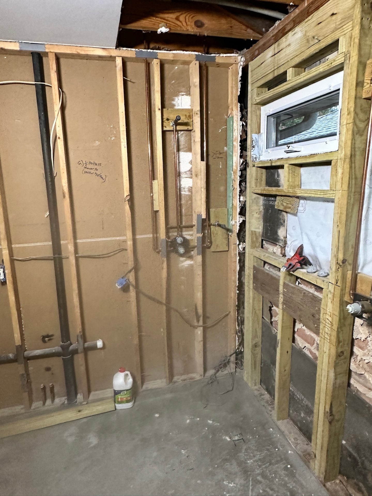 Wide corner of Metairie master bath rough-in showing copper supply, drain stack, and framed shower opening