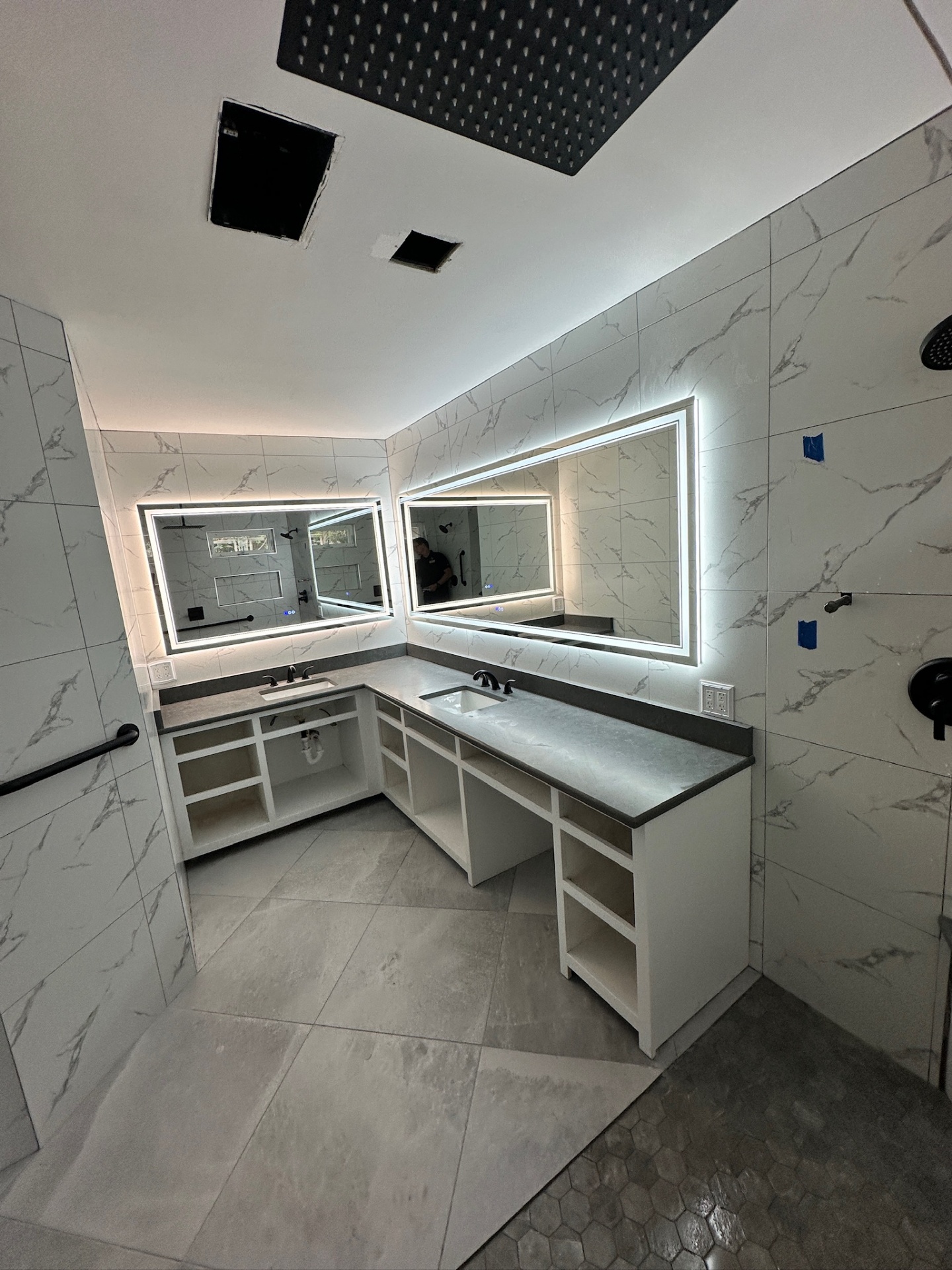 L-shaped dual-sink vanity installed with quartz counters and dual LED mirrors before doors and drawer fronts in Metairie master bath