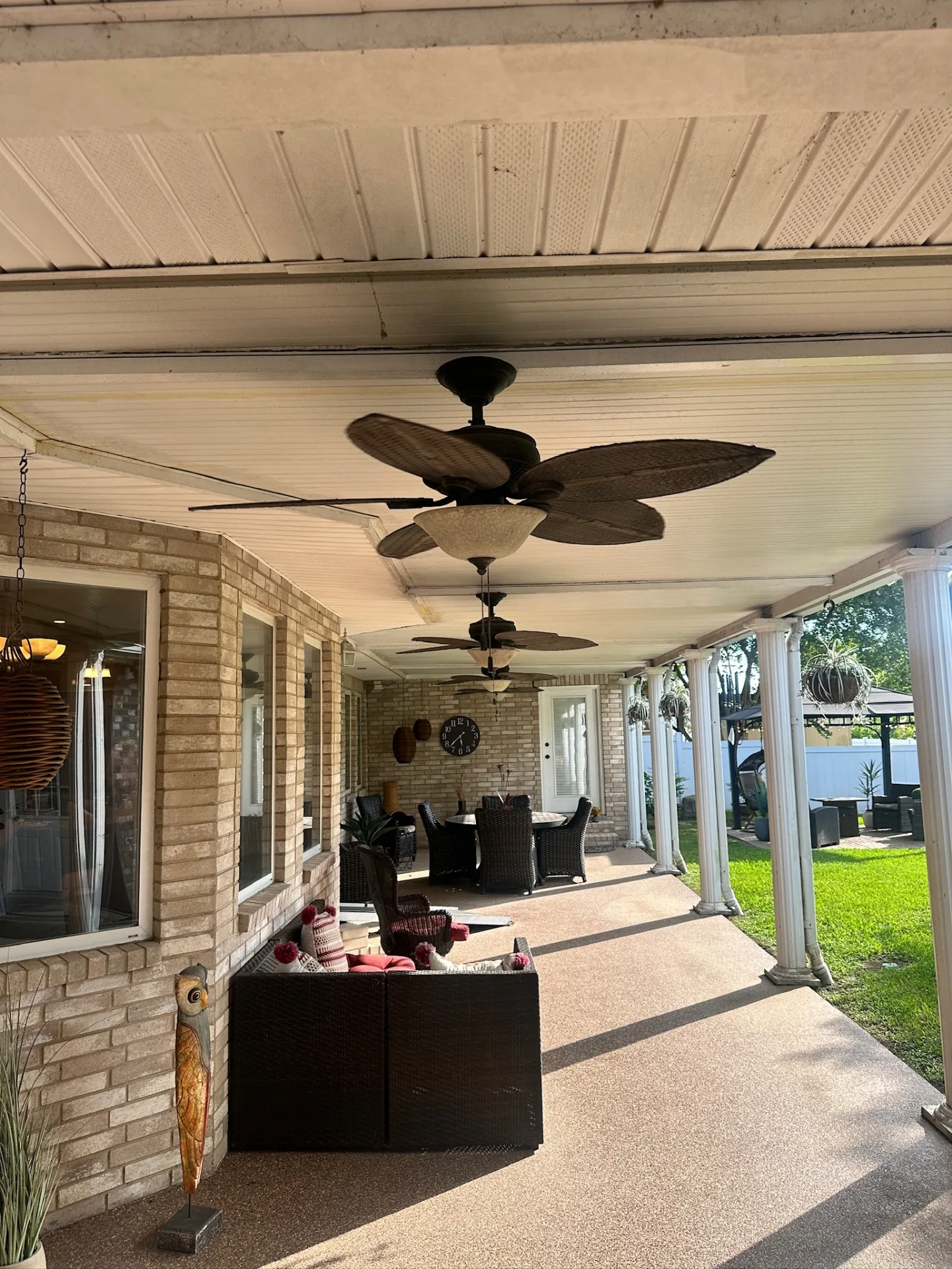 Wide before view of long covered patio with multiple ceiling fans, aluminum pan ceiling, and Corinthian columns on Destrehan Louisiana home