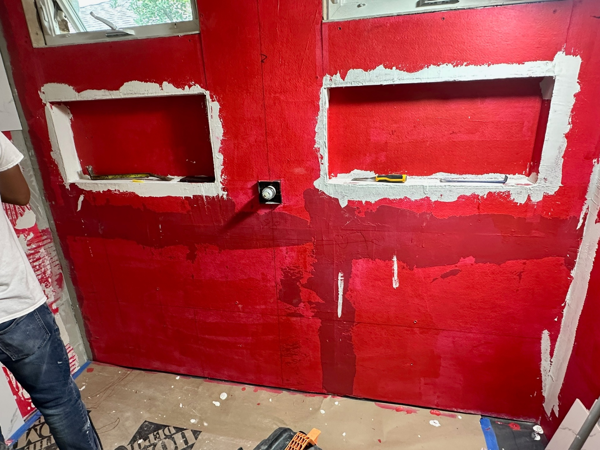 Close view of RedGard waterproofing around two framed shower niches with mortar-set backer edges in Metairie master bath