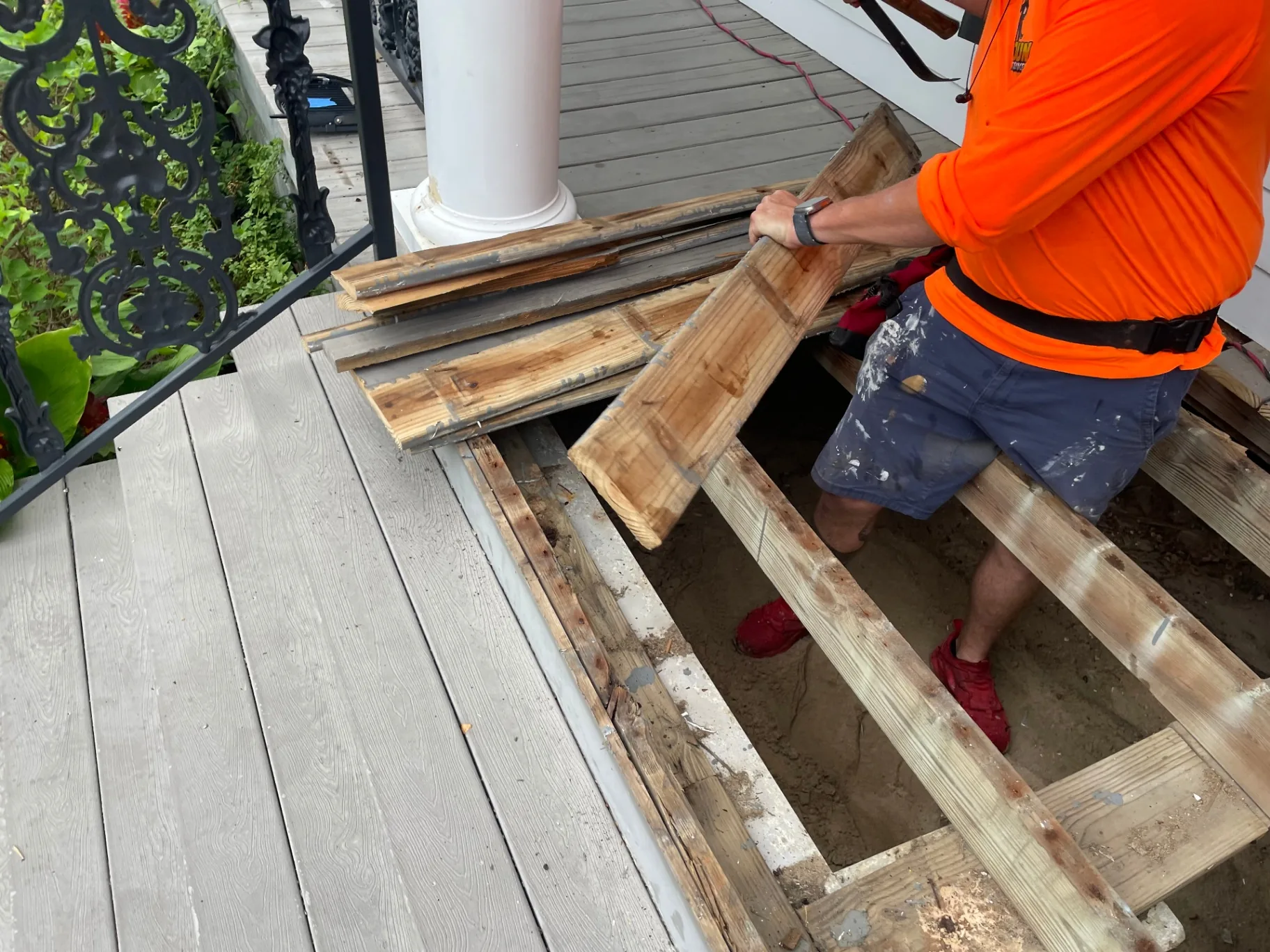 Cajun Home Services carpenter removing old wood decking planks from Algiers Point front porch during demo