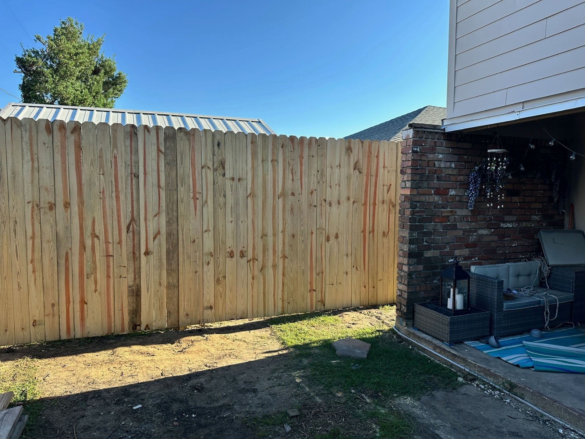 Finished picket fence tied into metal-roof shed on Bissonet Dr Metairie Louisiana