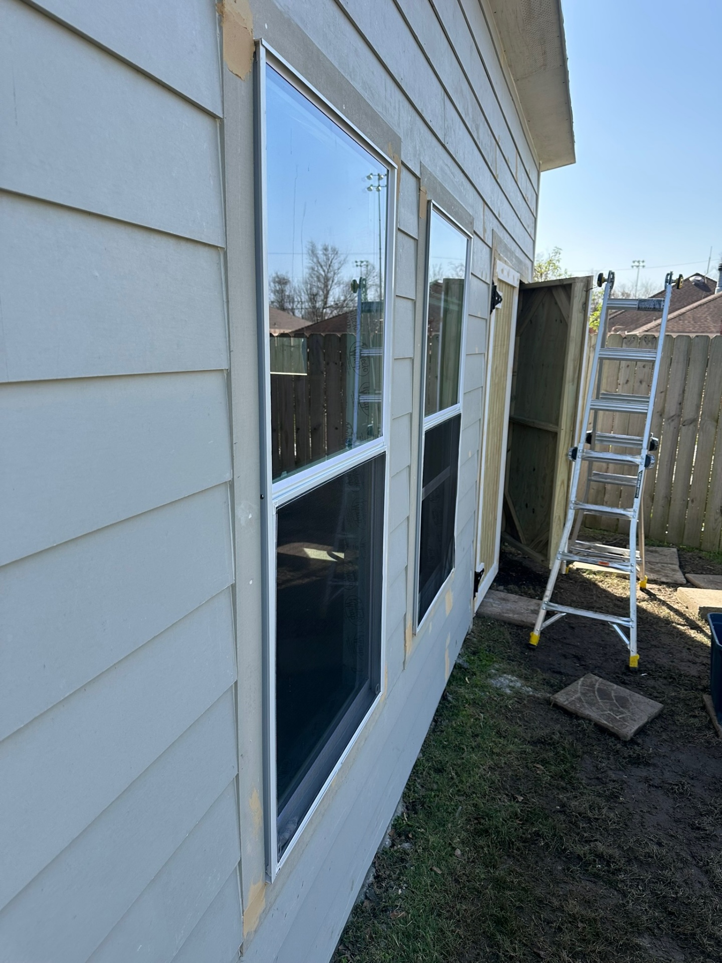 Side window pair of Metairie outbuilding with new vinyl windows set into flashed Hardie plank openings before trim and paint