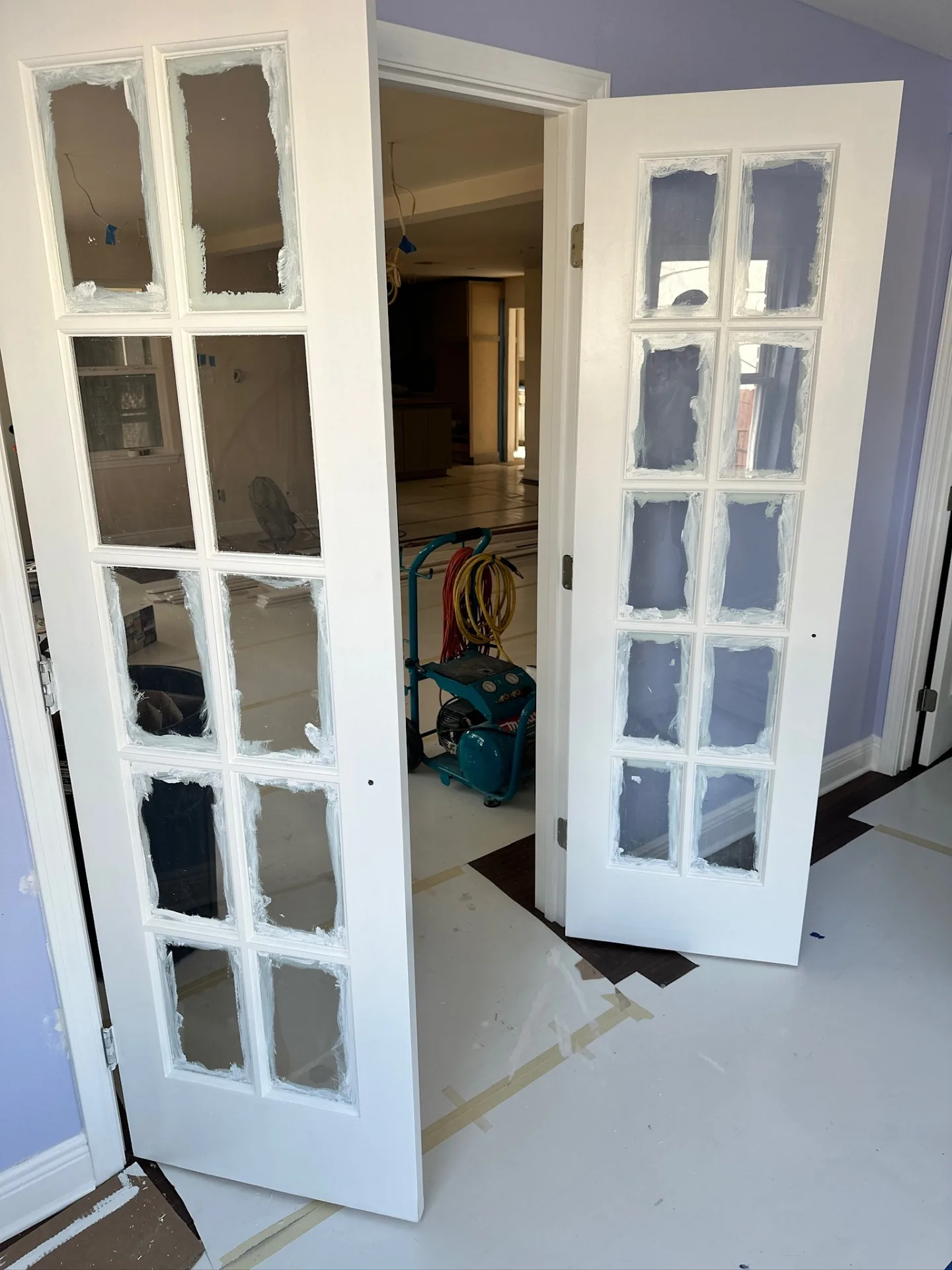 Pair of interior 15-lite French doors primed white and staged in the purple bedroom of Blanke Street Metairie whole-home remodel