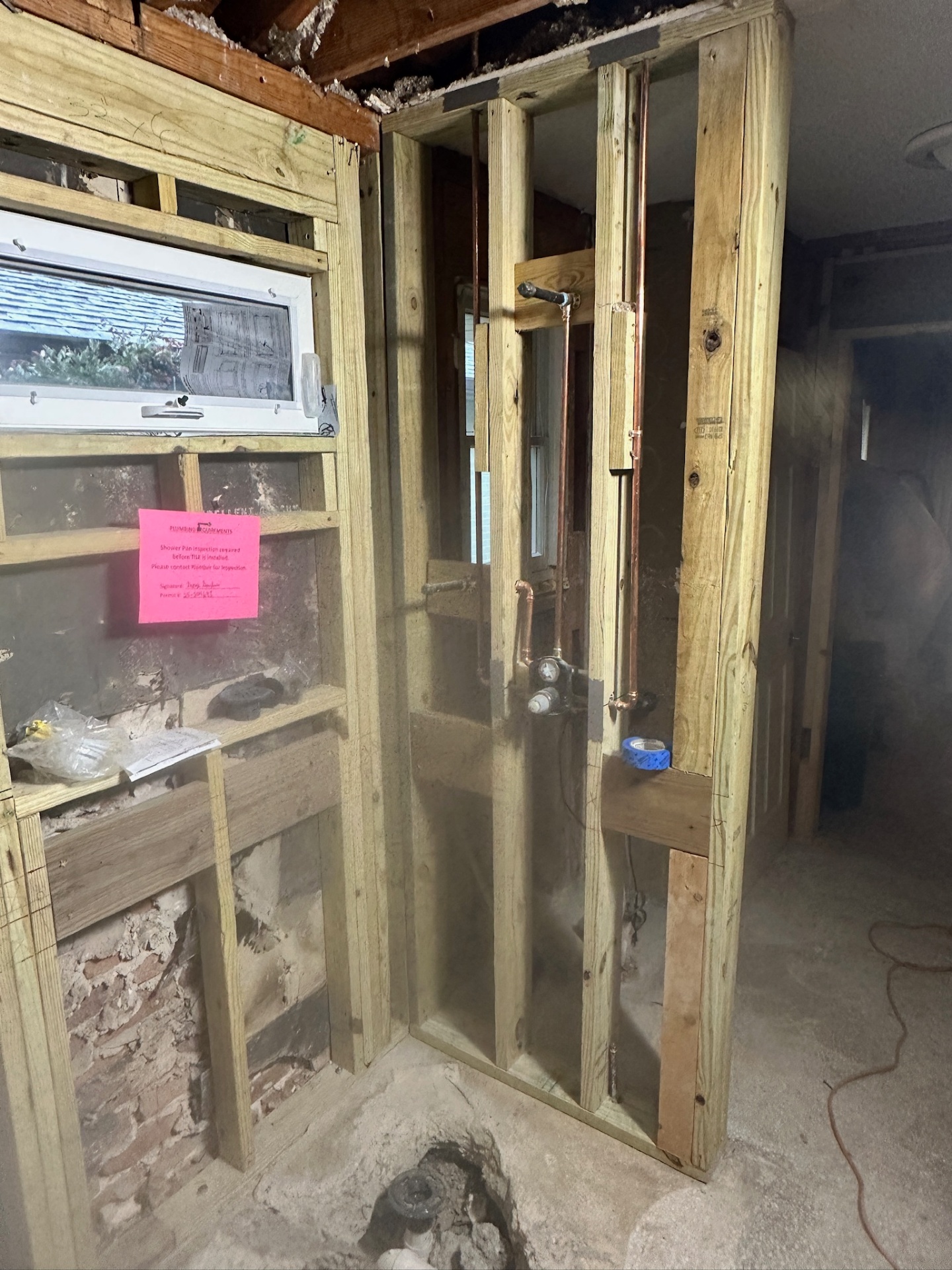 Corner view of framed walk-in shower with copper supply, mixing valve, and awning window in Metairie master bath