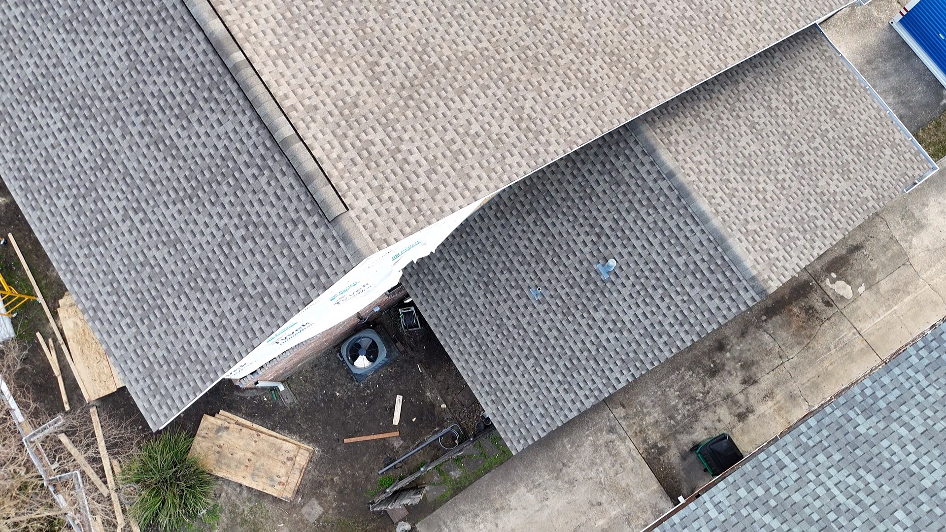 Aerial view of Metairie second-floor addition roof with architectural shingles installed on the main planes and synthetic underlayment still exposed in one valley mid-installation