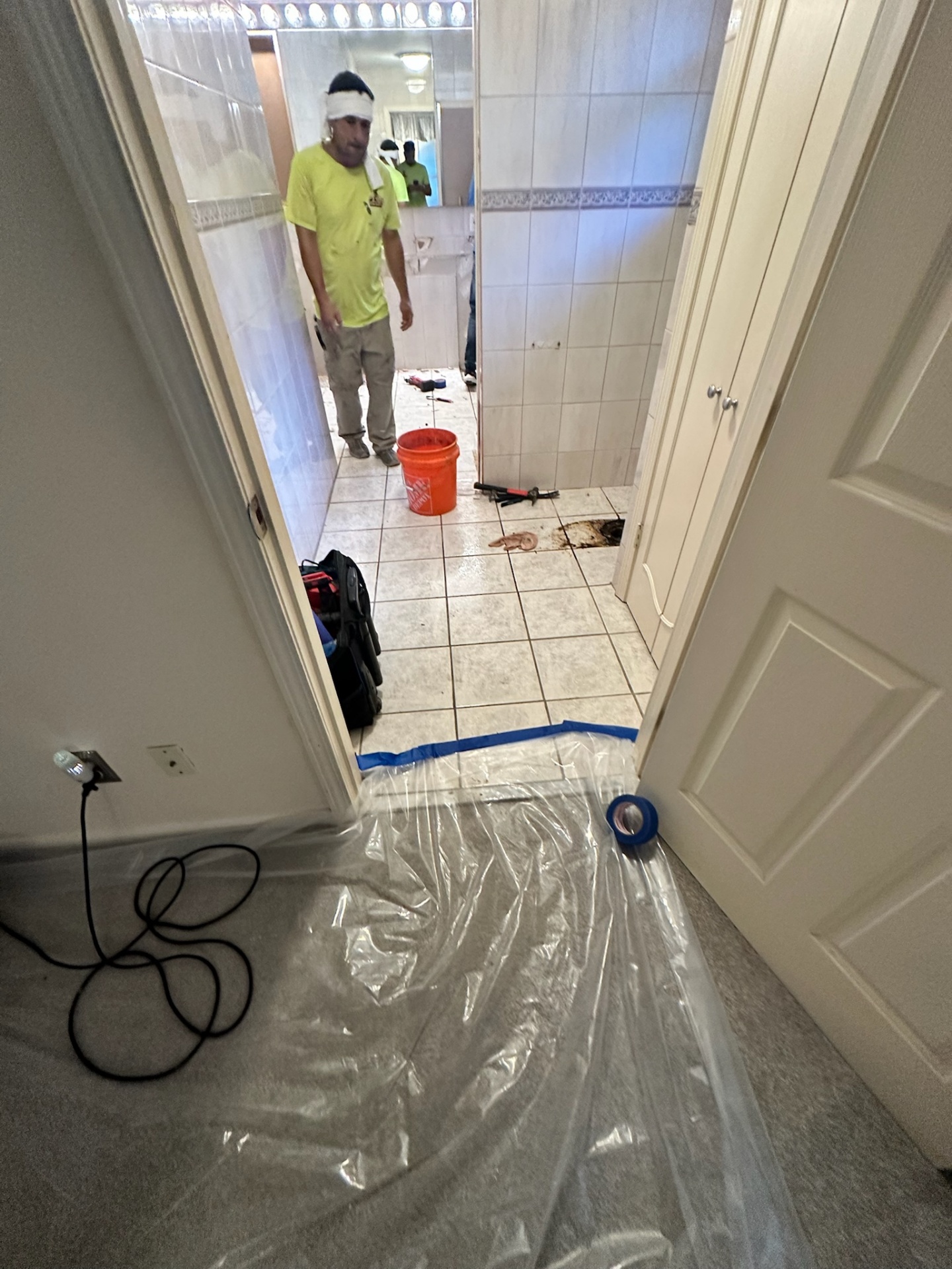 Cajun Home Services crew starting demo of dated Metairie master bath — plastic and blue tape protecting bedroom carpet