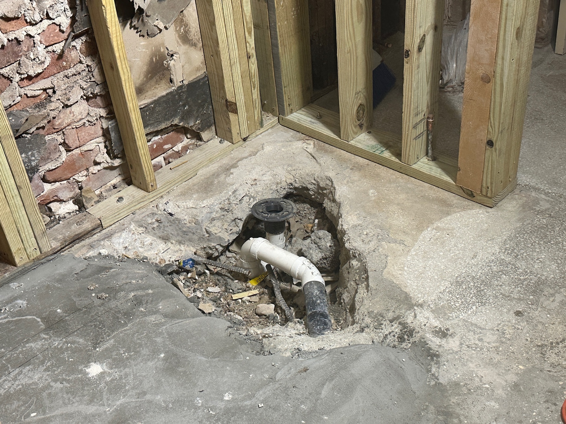New PVC toilet flange set in fresh concrete patch in Metairie master bath rough-in