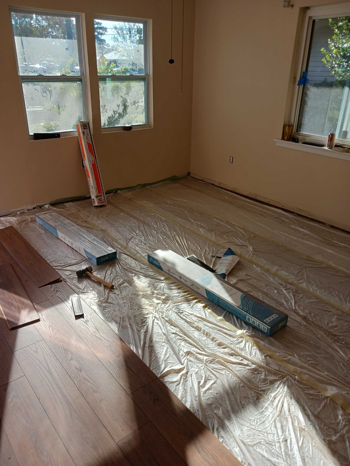 New laminate flooring installation in progress in a Gretna bedroom with moisture barrier underlayment down and planks stacked for install