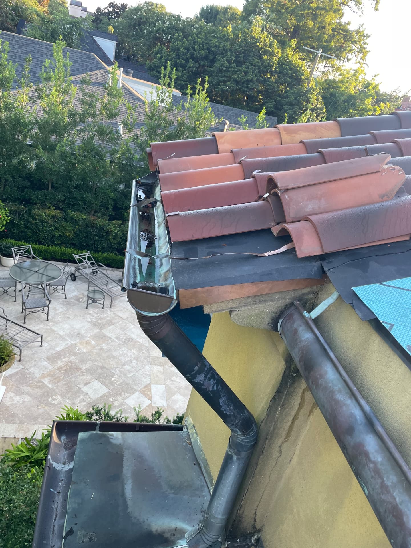 Tile eave torn open showing new underlayment, copper flashing, and a rebuilt gutter edge in Metairie Louisiana