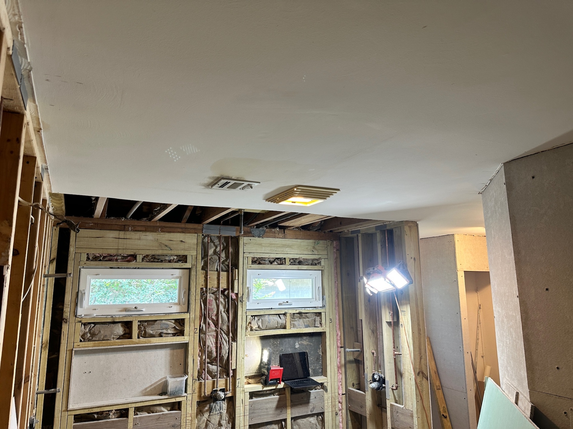 New drywall ceiling finished with insulation-filled framing still open in Metairie master bath remodel