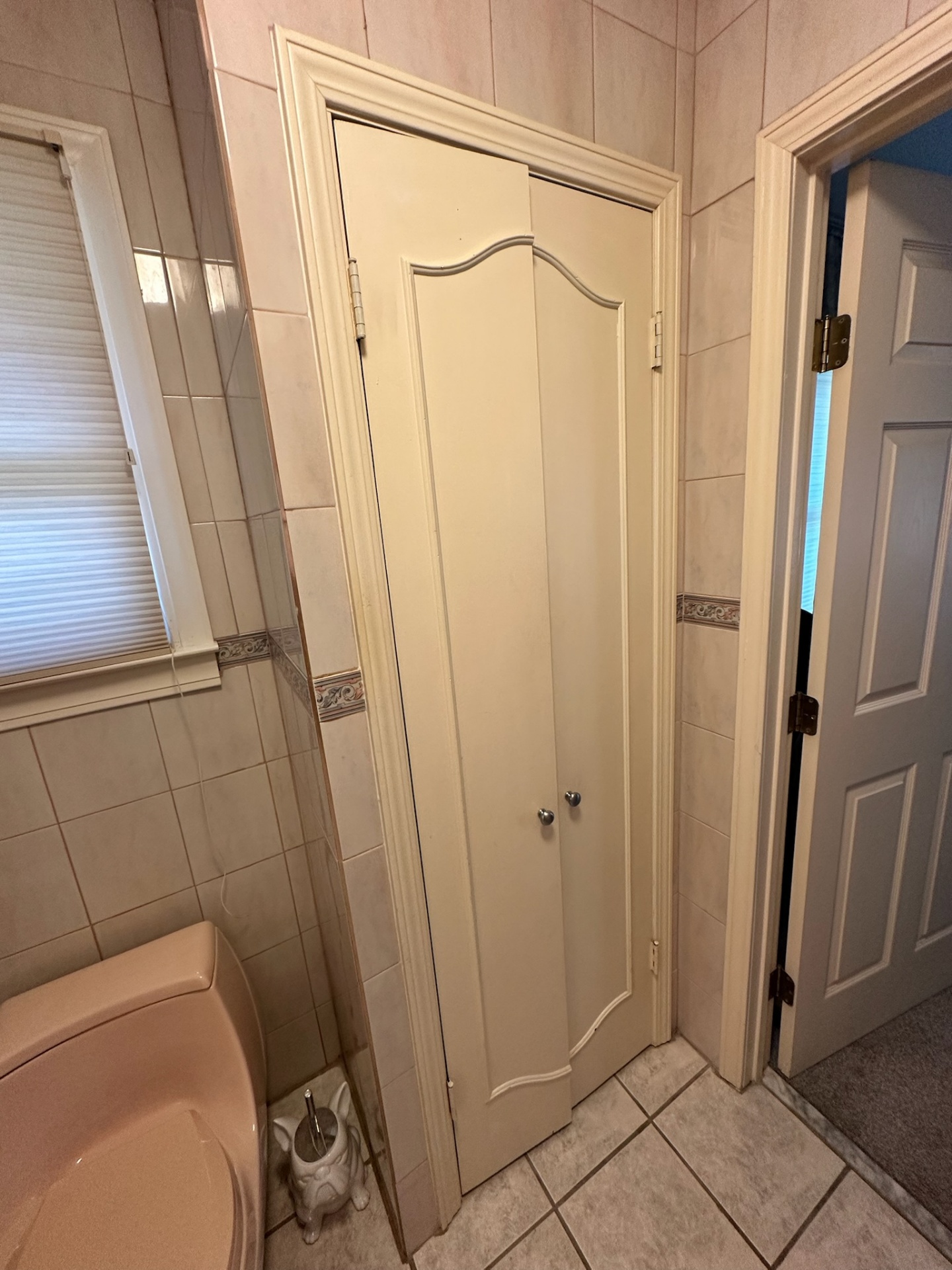 Before — arched linen closet doors and toilet area with dated tile in Metairie master bath