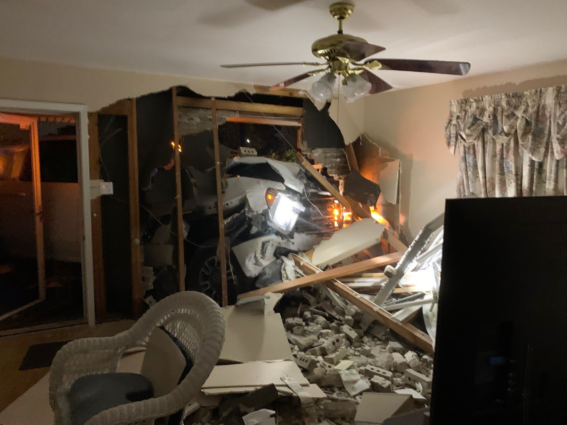 Pickup truck crashed through the front exterior brick wall of a Gretna Louisiana home, viewed from the interior living room at night