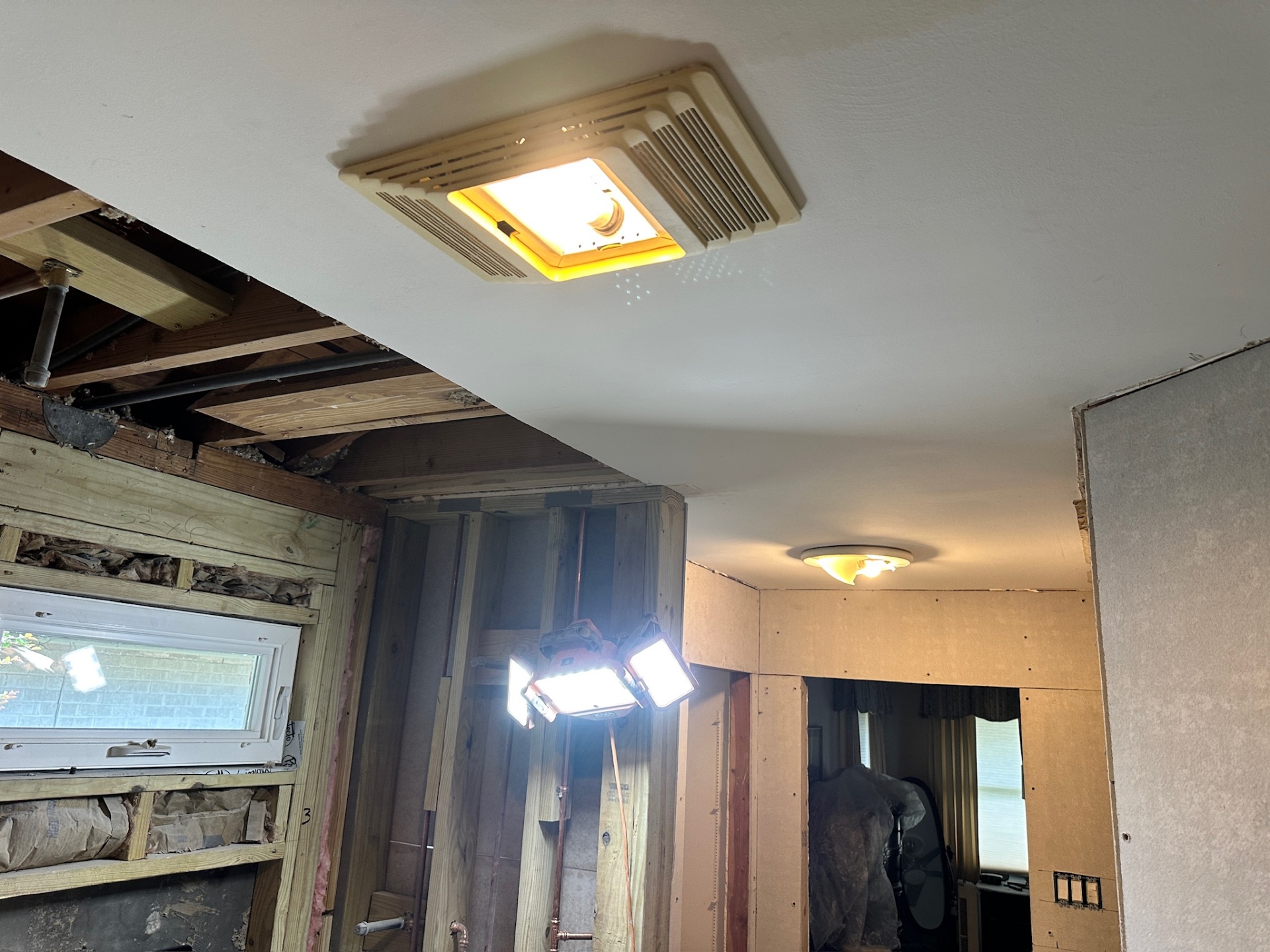 Old builder bath fan being removed as ceiling drywall goes up in Metairie master bath