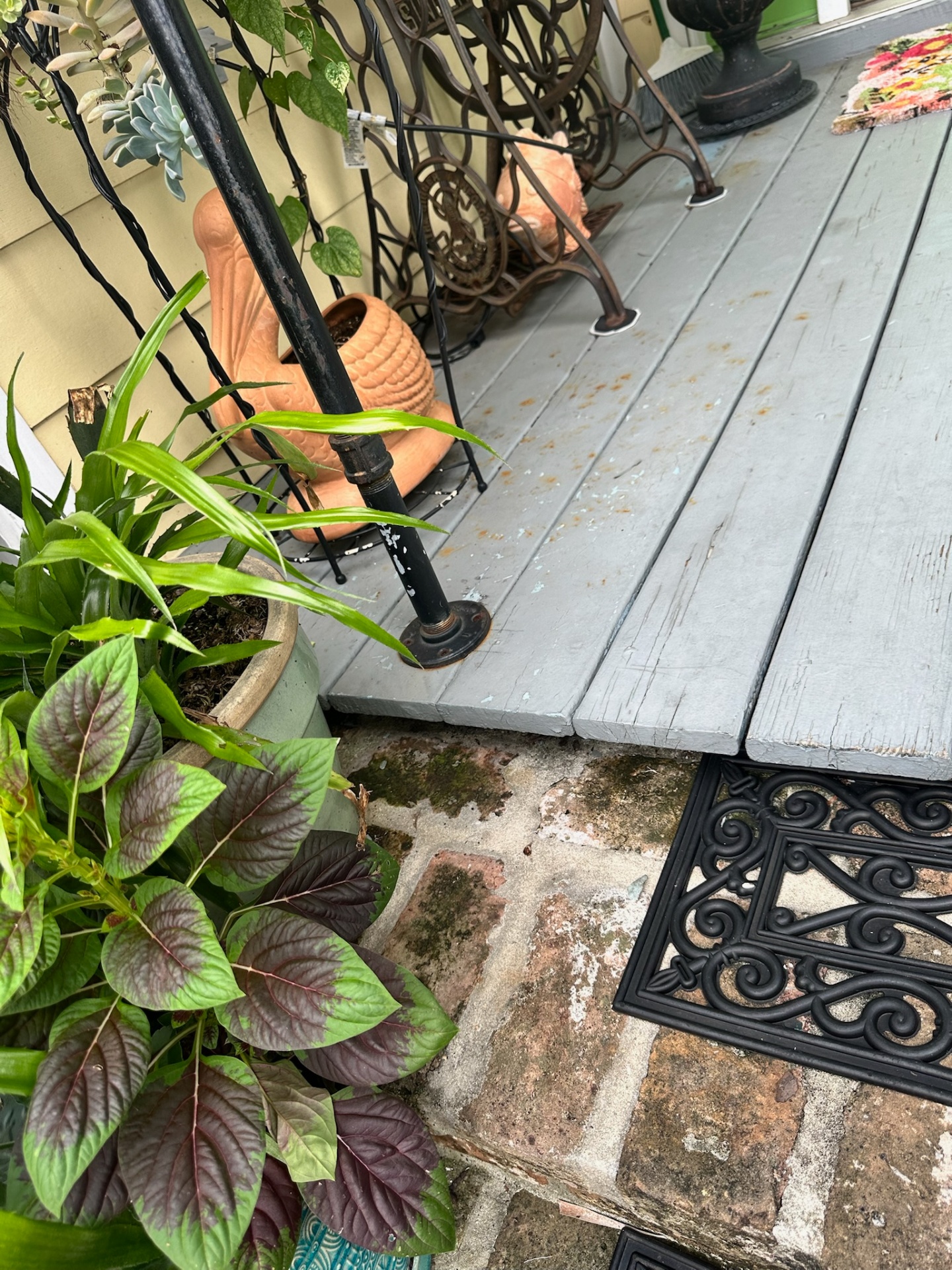 Before — weathered porch boards meeting original brick step in Algiers Point