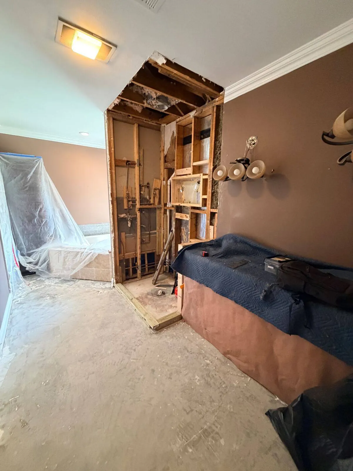 Master bathroom demolition with shower stall removed exposing wall framing and plumbing rough-in during remodel in Destrehan LA