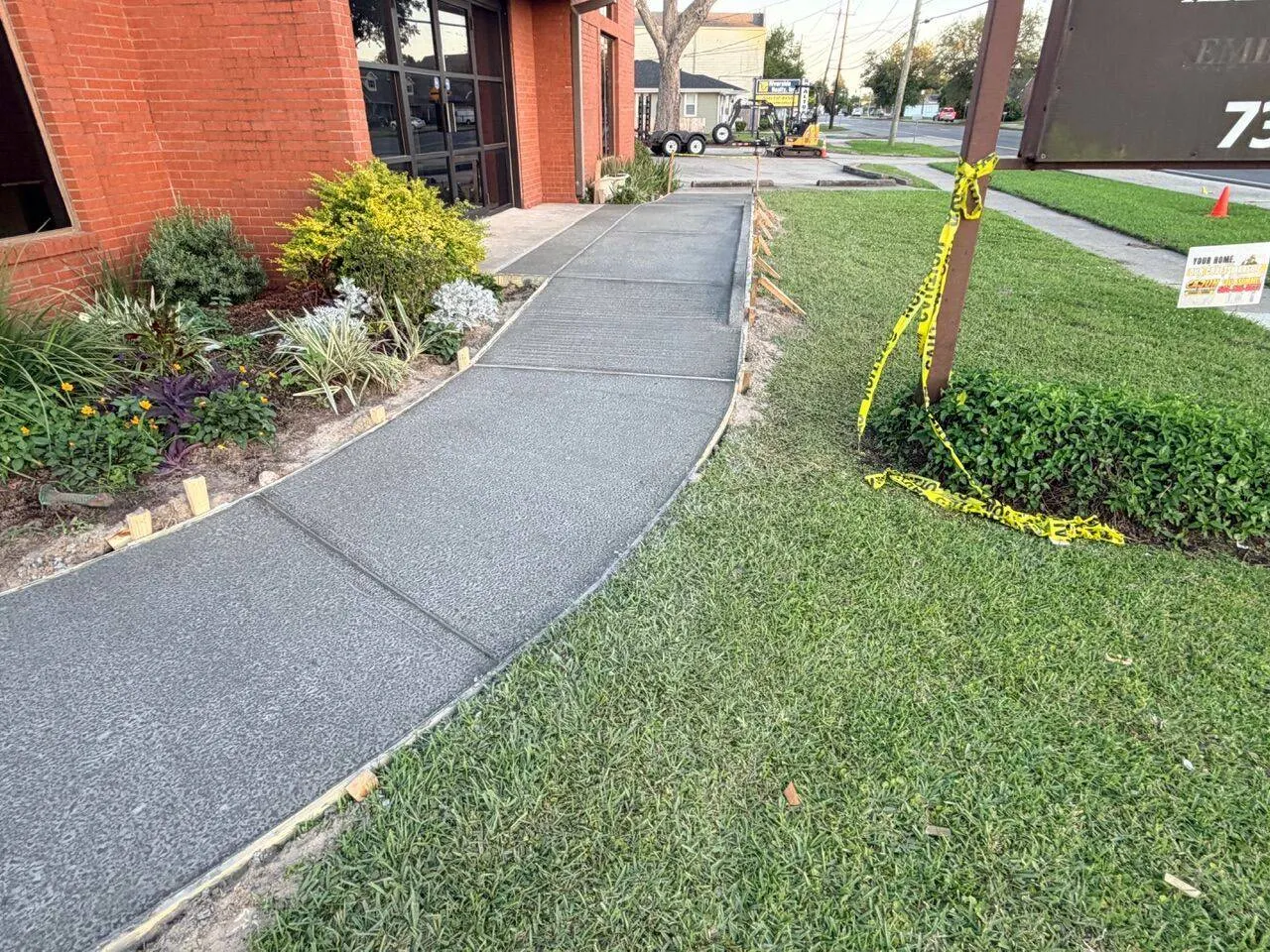 Completed curved concrete walkway with broom finish leading to commercial dentistry office entrance in River Ridge Louisiana