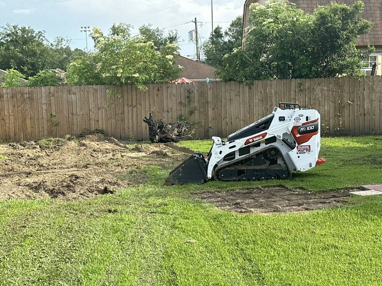 Bobcat MT100 skid steer performing backyard grading and excavation for new construction site prep in Metairie