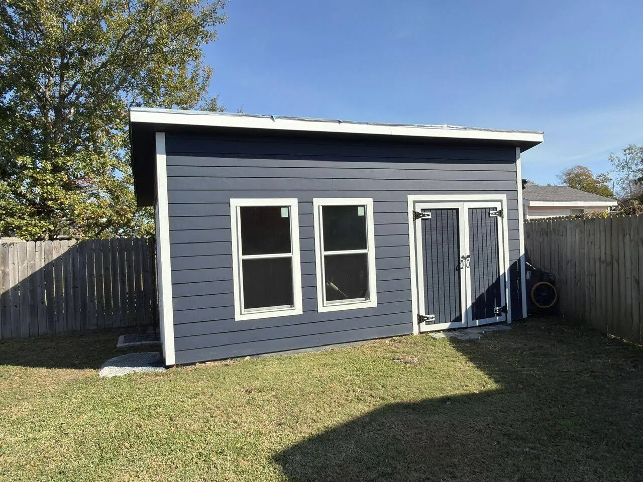 Completed custom shed alternate angle showing navy siding and window in Metairie LA