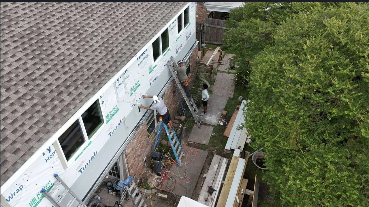 Aerial drone view of crew installing Hardie plank siding on second floor addition in Metairie LA