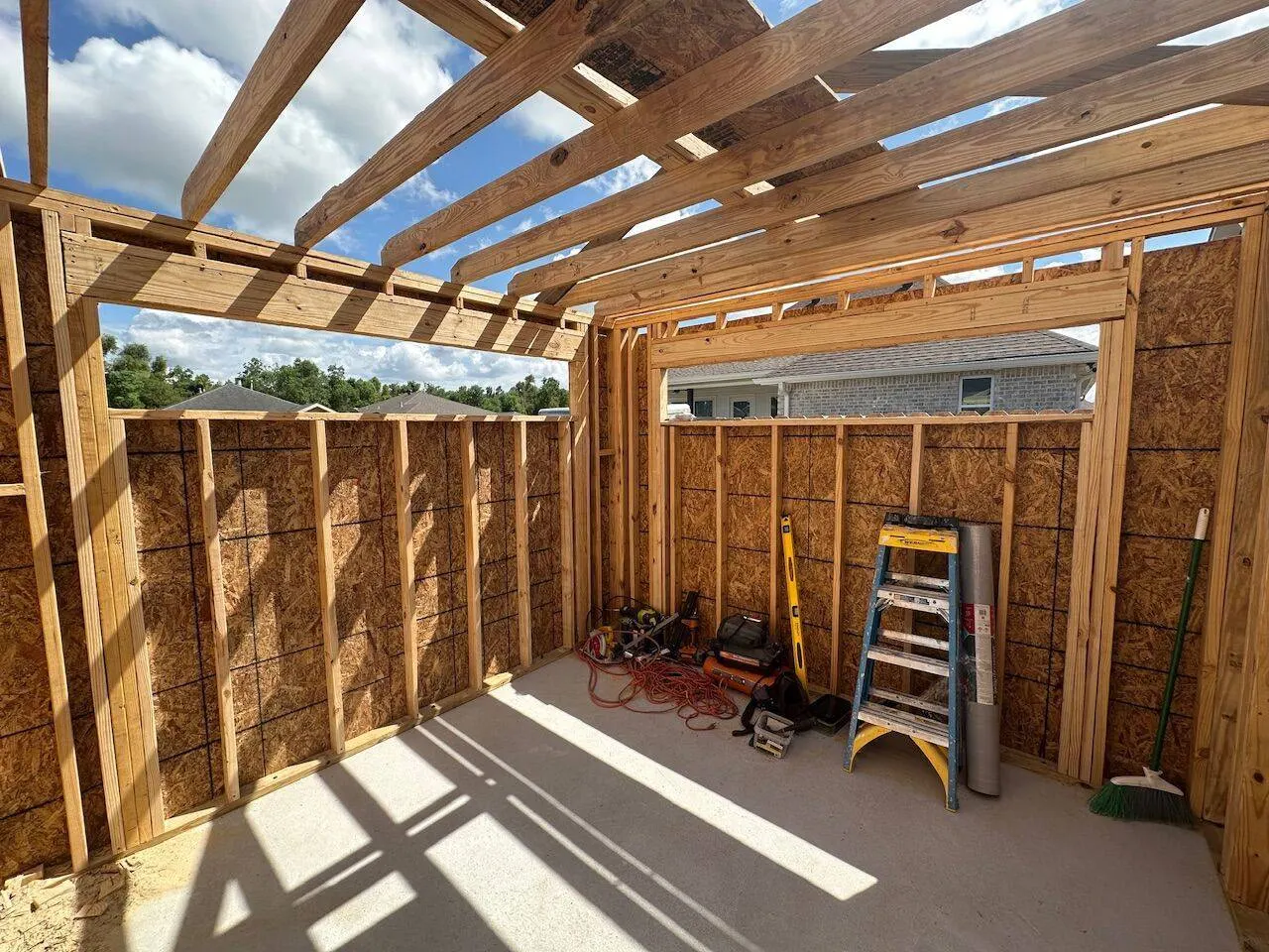 Interior view of new construction framing with rafters and tools on concrete slab in Meraux LA